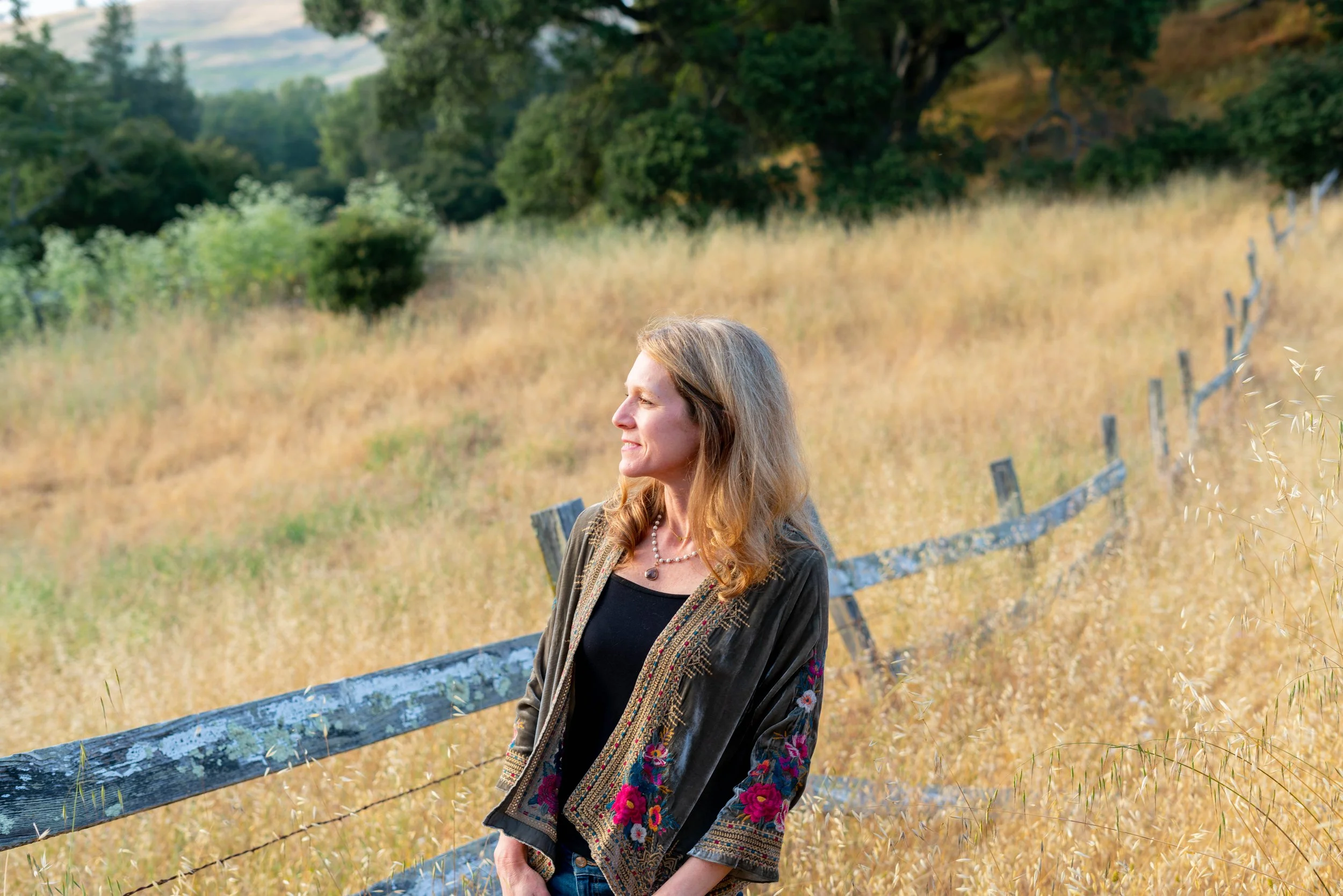 Jodie Stein MFT in nature next to a fence overlooking a valley view