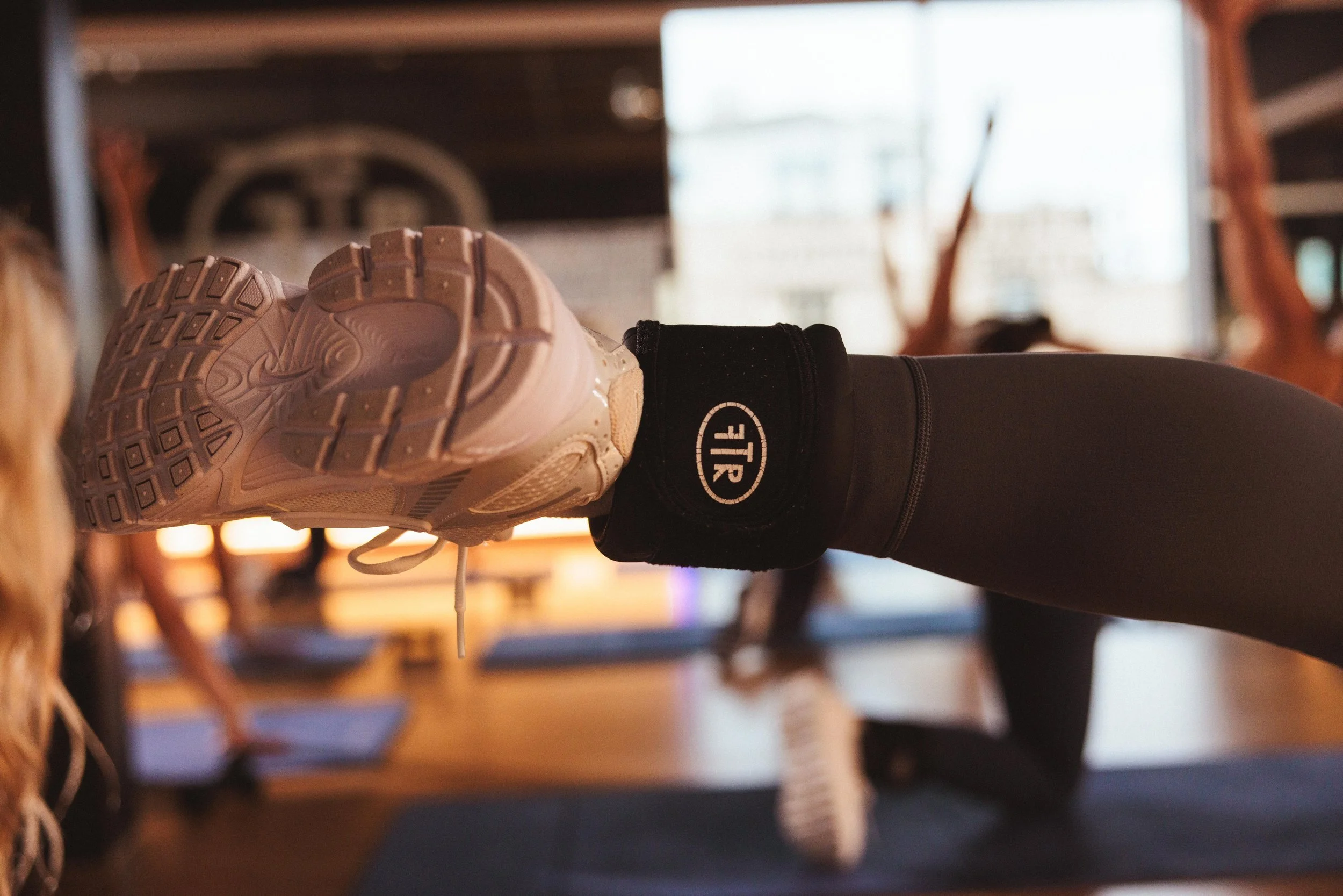 foot kicks to the left with a white athletic shoe and ankle weight with the full routine logo