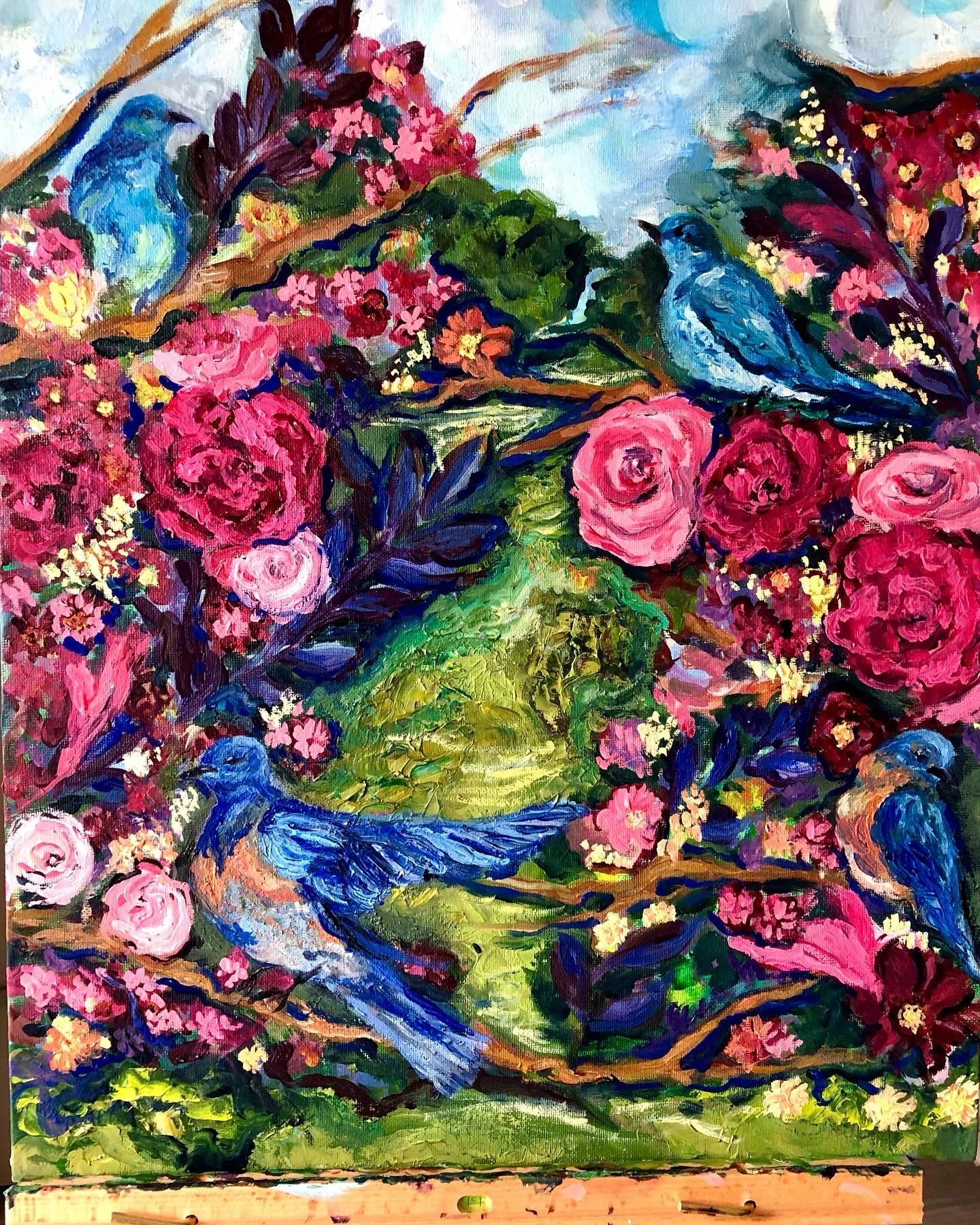 A colorful oil painting of two blue birds perched on a branch amid pink and purple flowers, with green foliage and a light sky background.
