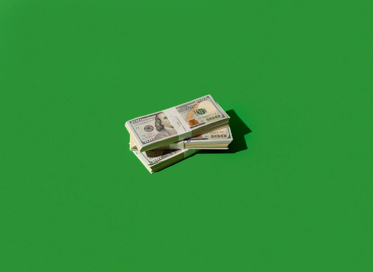 Stacks of 100-dollar bills on a bright green background.