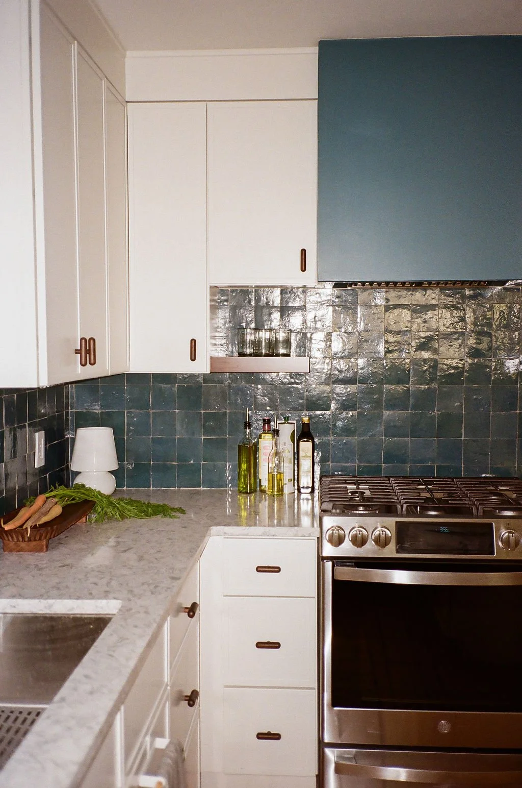 A close up of the custom vent hood in Jordyn Garcia Studio's Modern Mediterranean Kitchen. The vent hood is painted in a Aegean Sea paint color by Benjamin Moore. The shade matches the zellige tile backsplash.