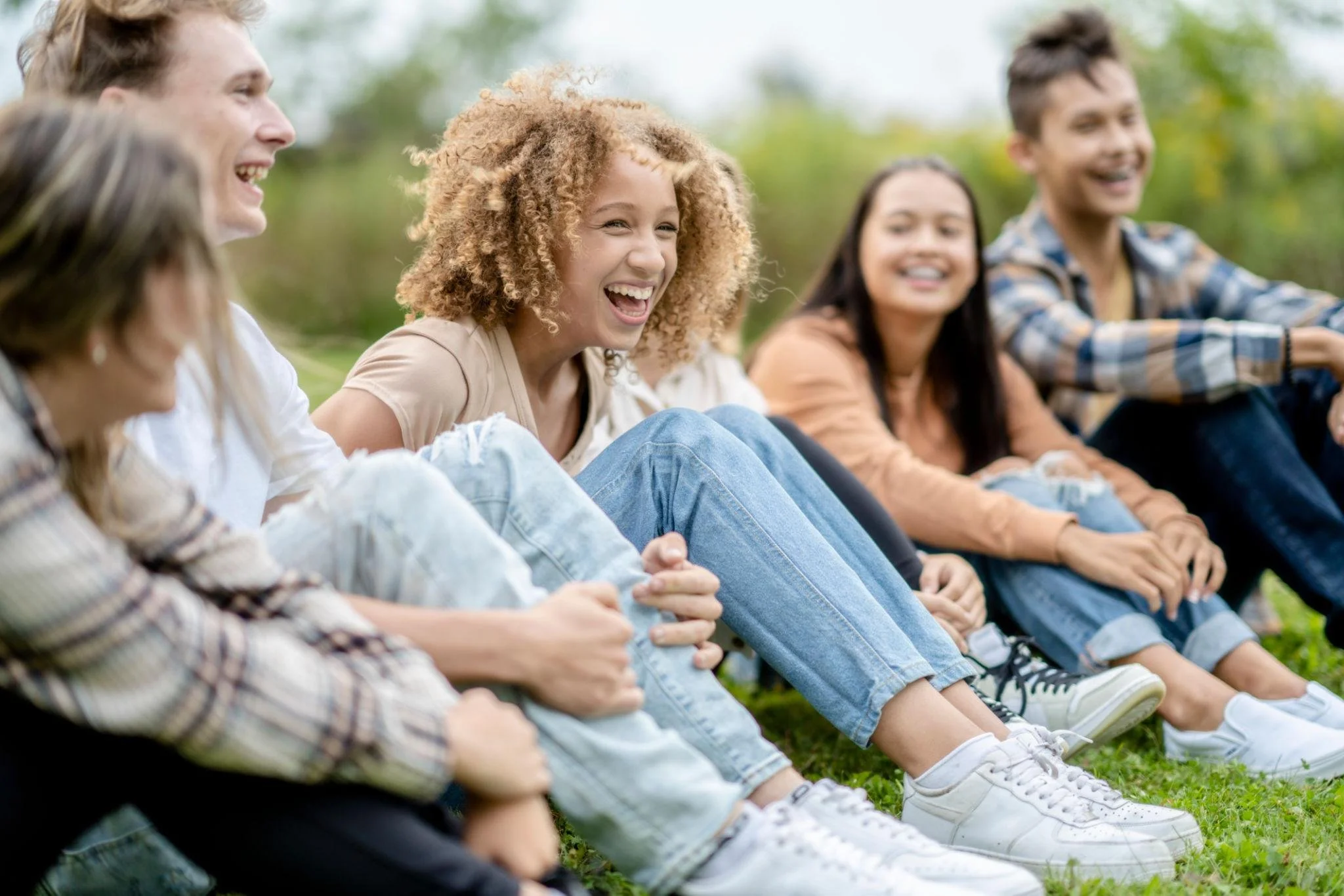 Diverse group of happy teenagers laughing together, showing friendship, resilience, and positive mental health wellness.