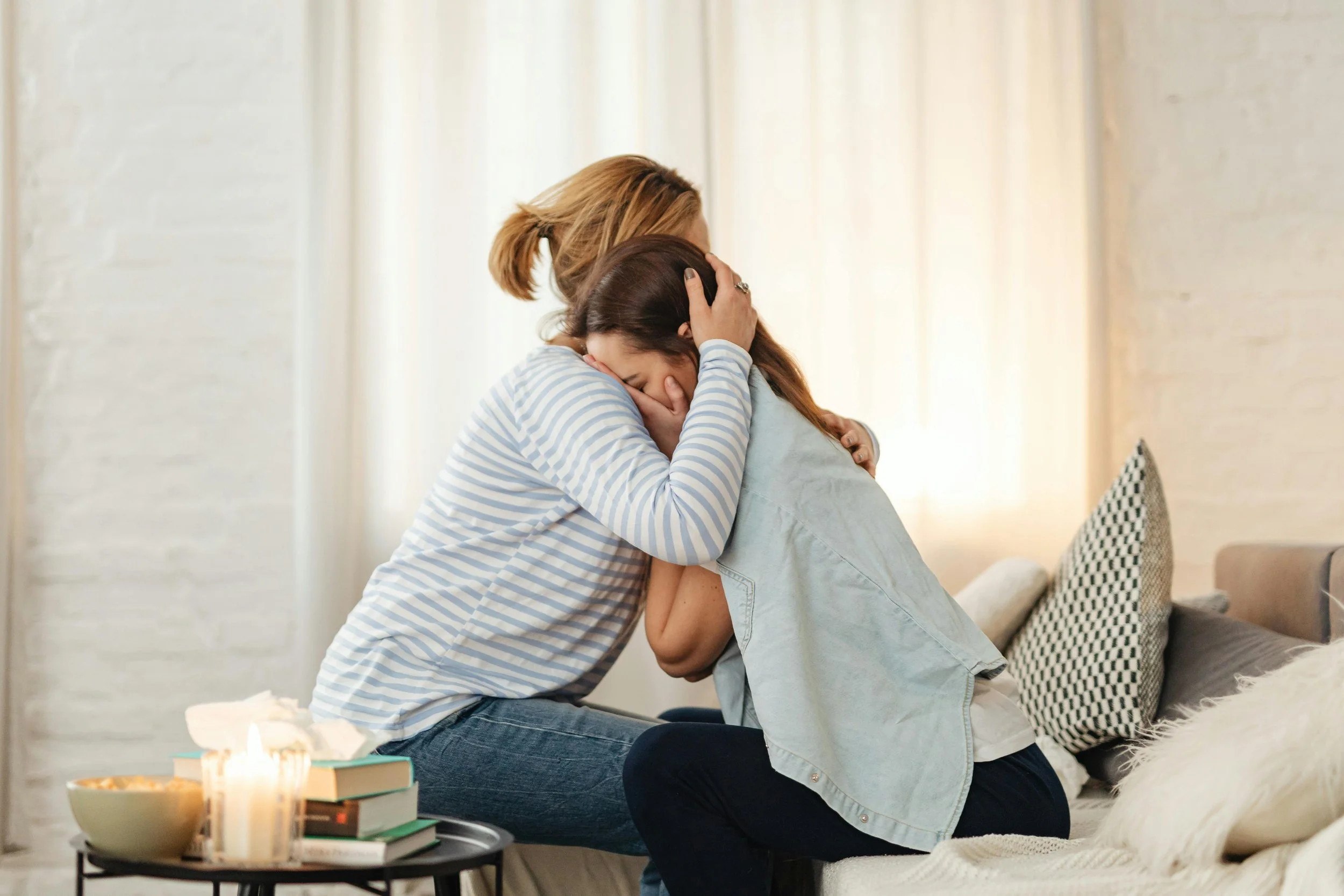 Mom offering comfort to her teen daughter, reflecting emotional support and family connection.