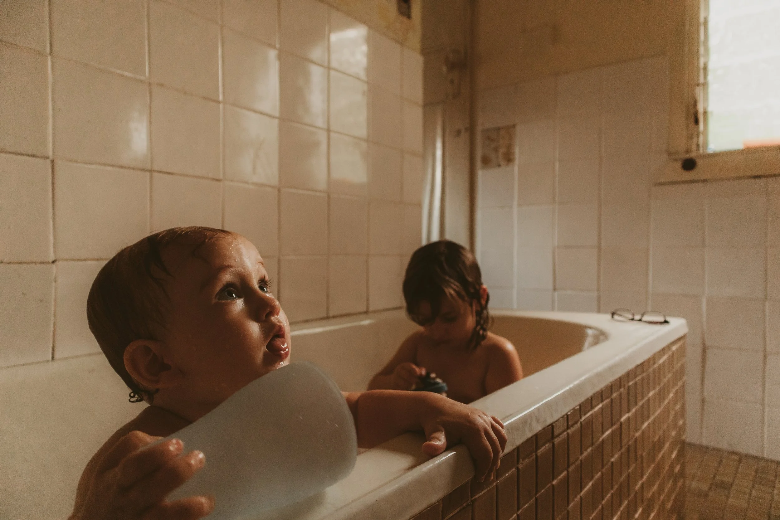 Brother and sister playing in the bath. Rustic, vintage motherhood photography