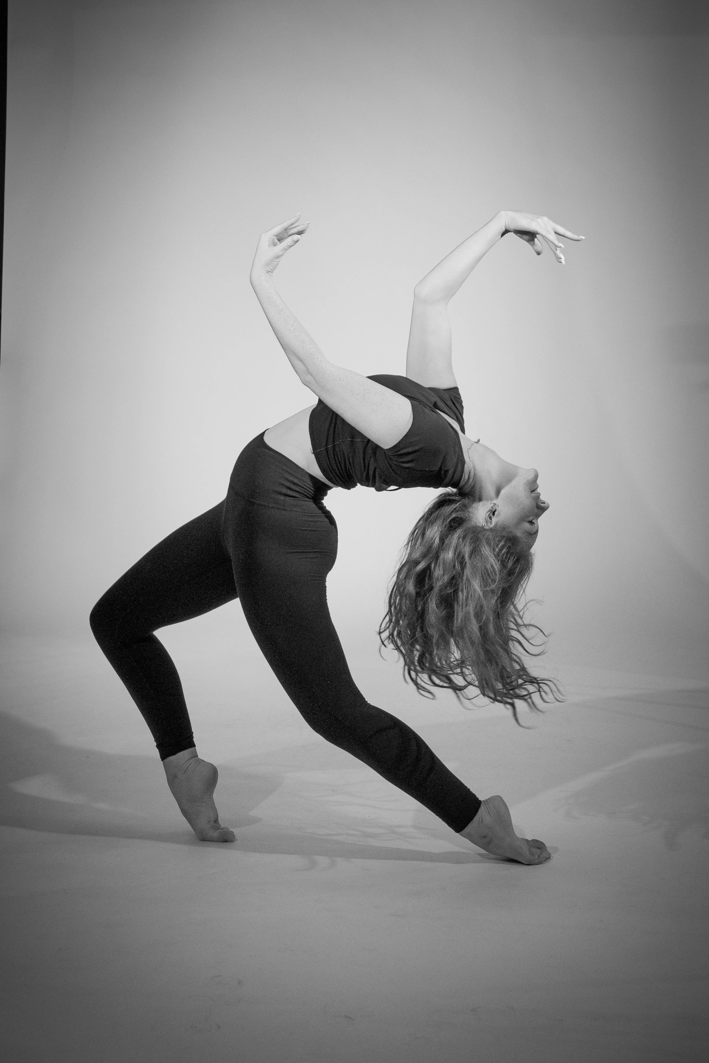 A woman performing a yoga pose in a studio, captured in black and white.