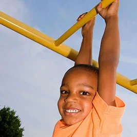 Child hanging from monkey bars at a playground