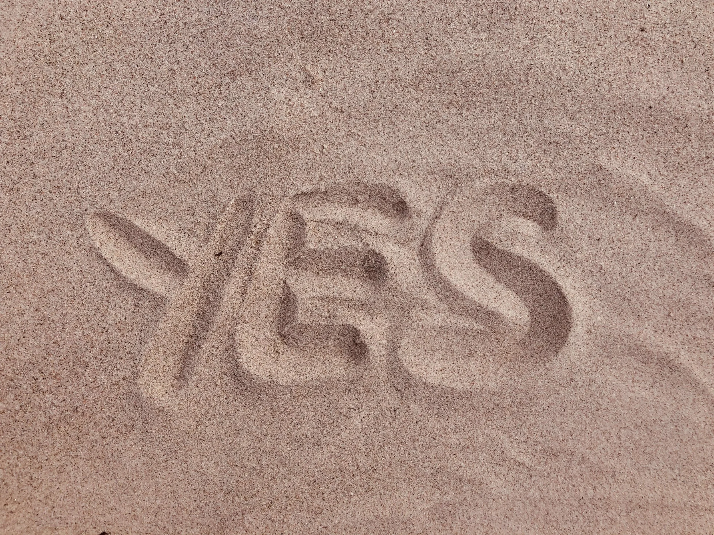 The word yes written in the sand