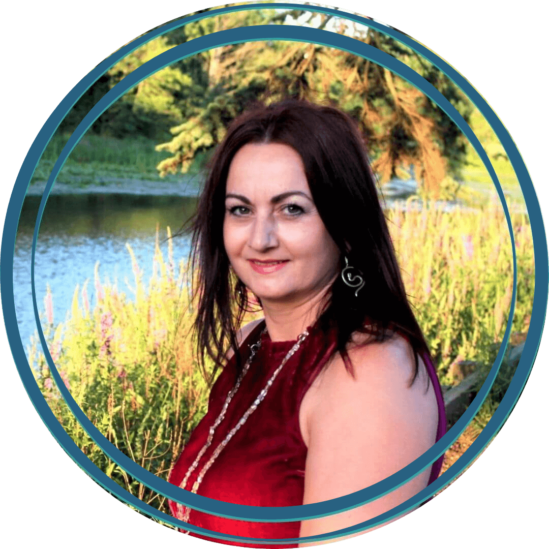 Picture of lady with long dark hair in nature wearing a deep red top and a chain necklace