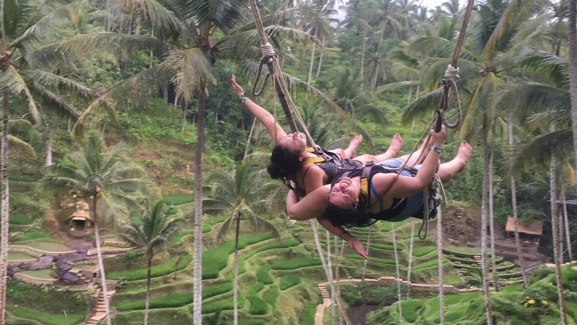 A mother and daughter on a swing through the jungle in Bali