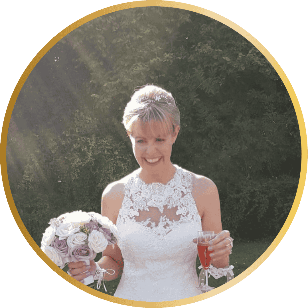 Lady with blonde hair in a white sleeveless wedding dress holding flowers and a glass
