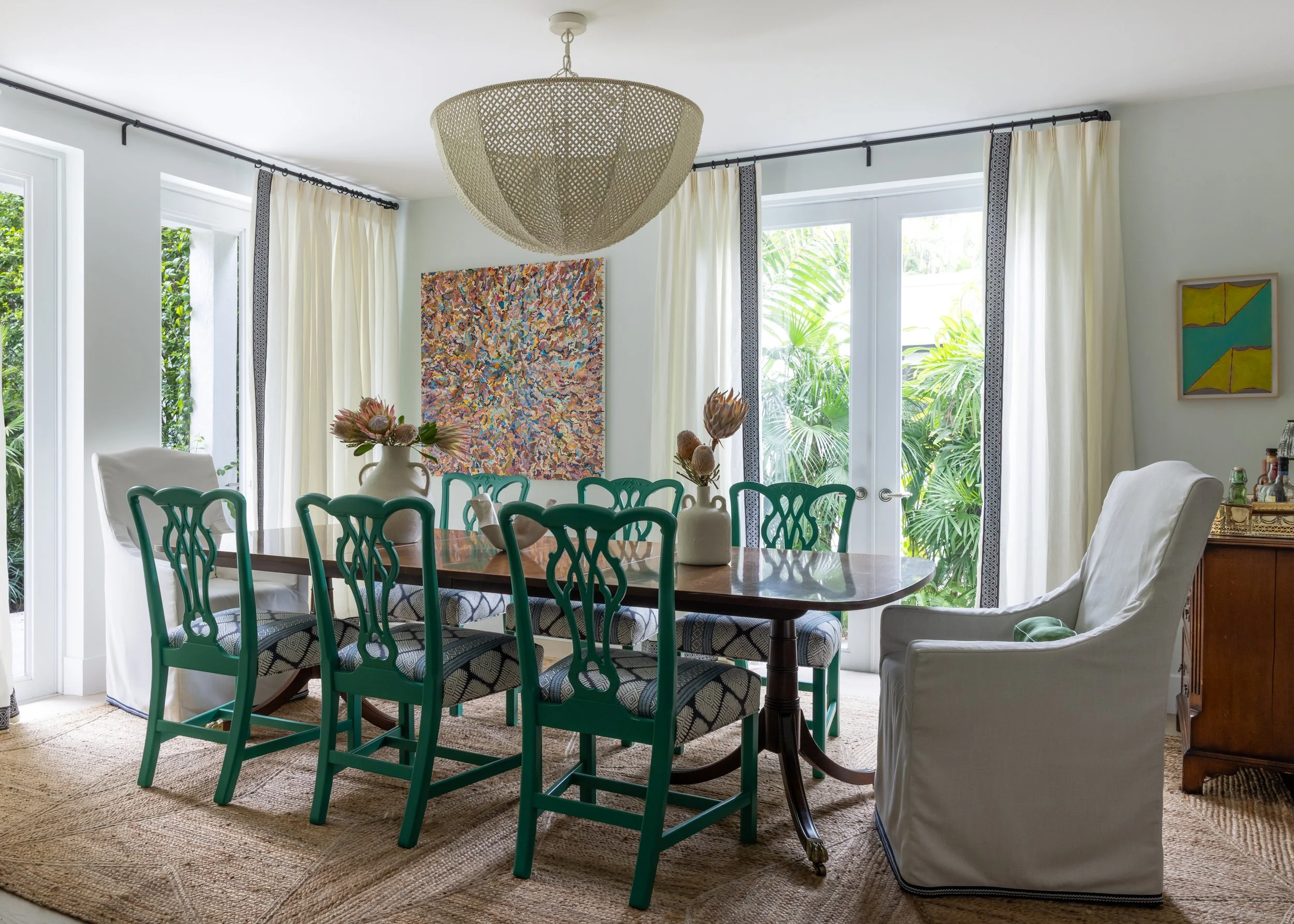 Bright dining room with Ming style coffee table, linen end chairs, and green dining chairs with dark blue patterned cushions, and a neutral jute rug in Imparfait designed space Crawford
