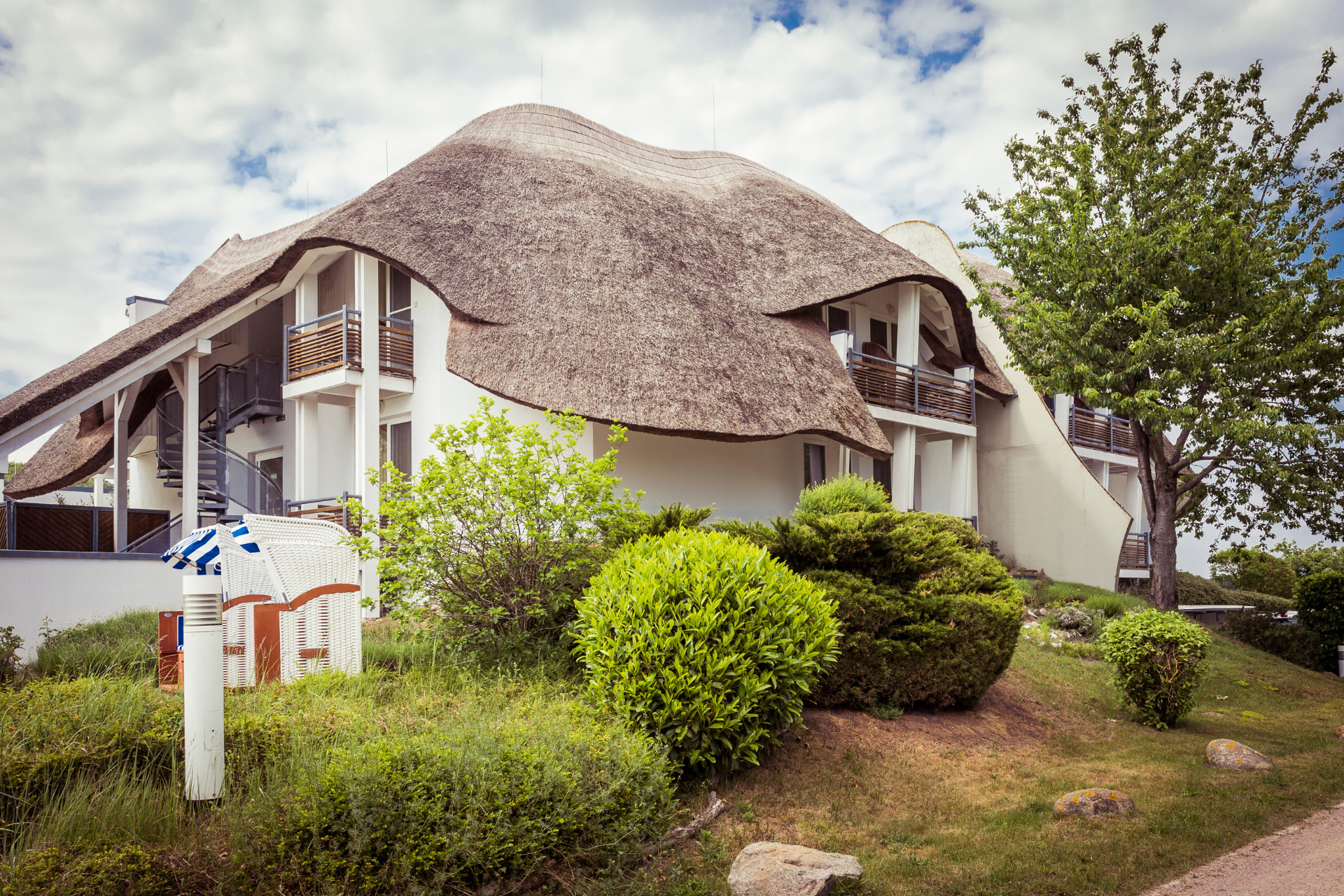 Hier ist eine Aufnahme des Hotel Solthus von Außen, das die wunderschöne Reetarchitektur des Hauses zeigt.