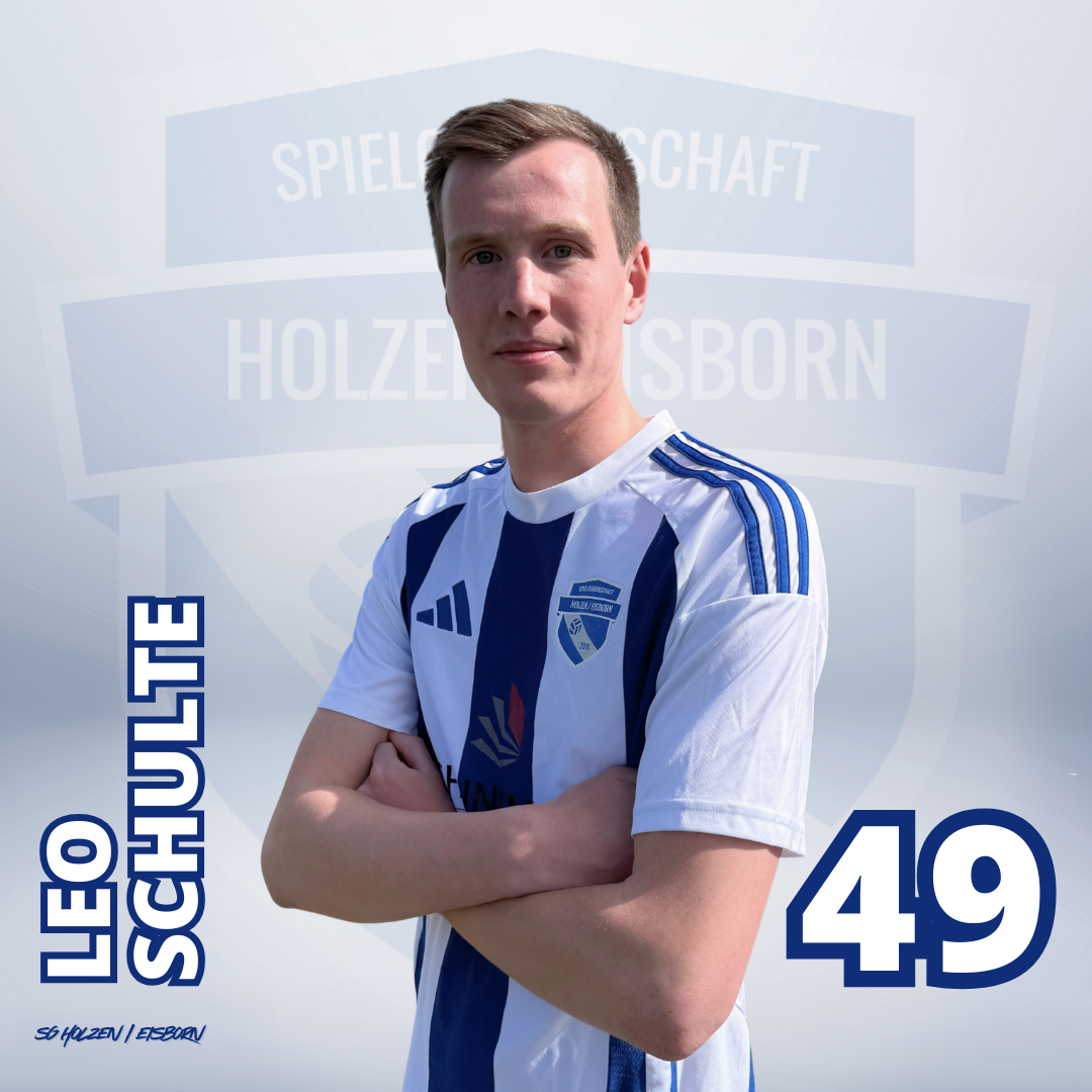 Ein junger Mann in einem blauen Fußballtrikot, der lächelnd mit verschränkten Armen vor einem Hintergrund mit einem grauen Wappen, das die Worte 'Spielgemeinschaft Holzen Born' trägt.