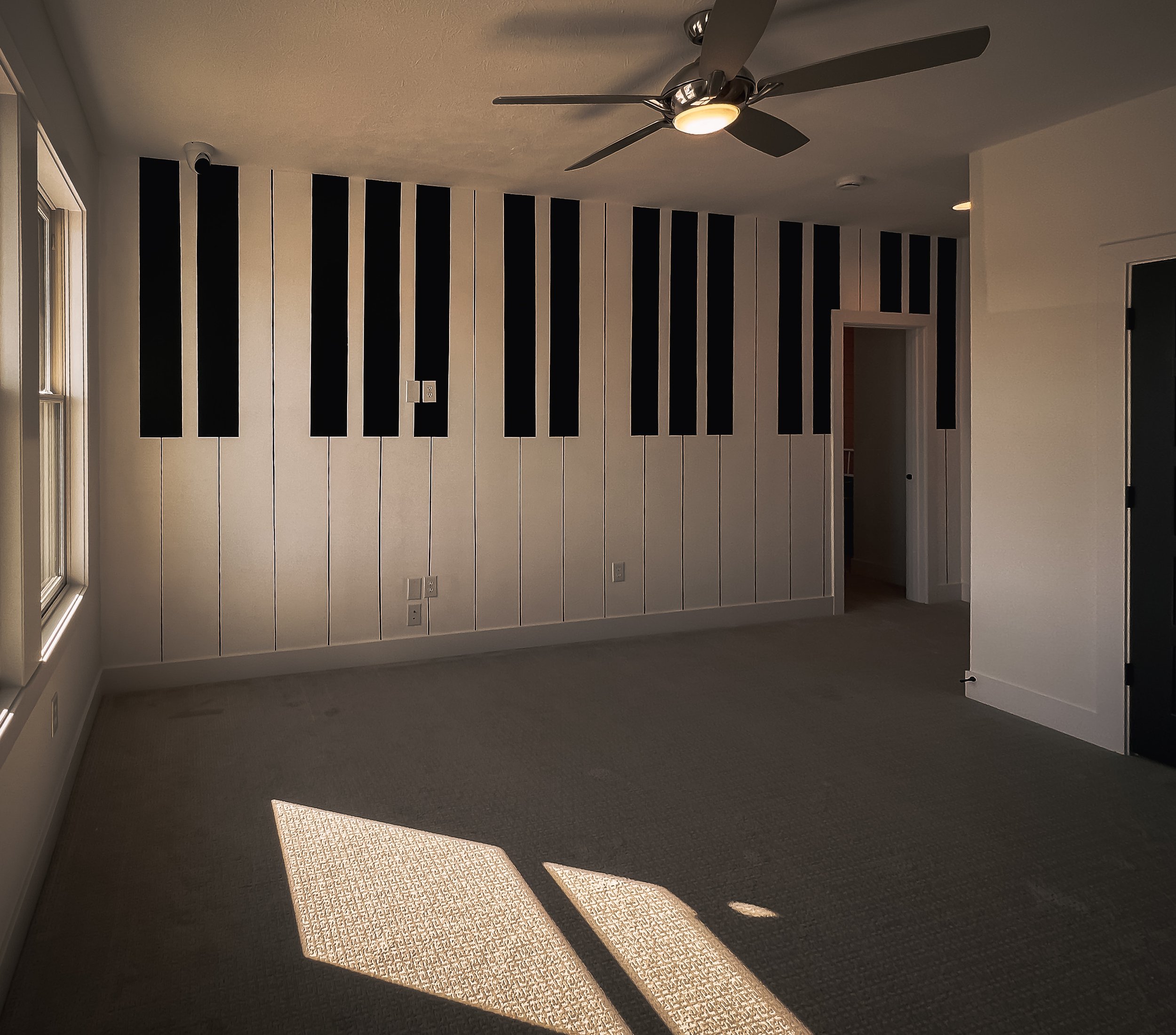 Black-and-white piano key mural painted across a paneled wall in a residential music room.