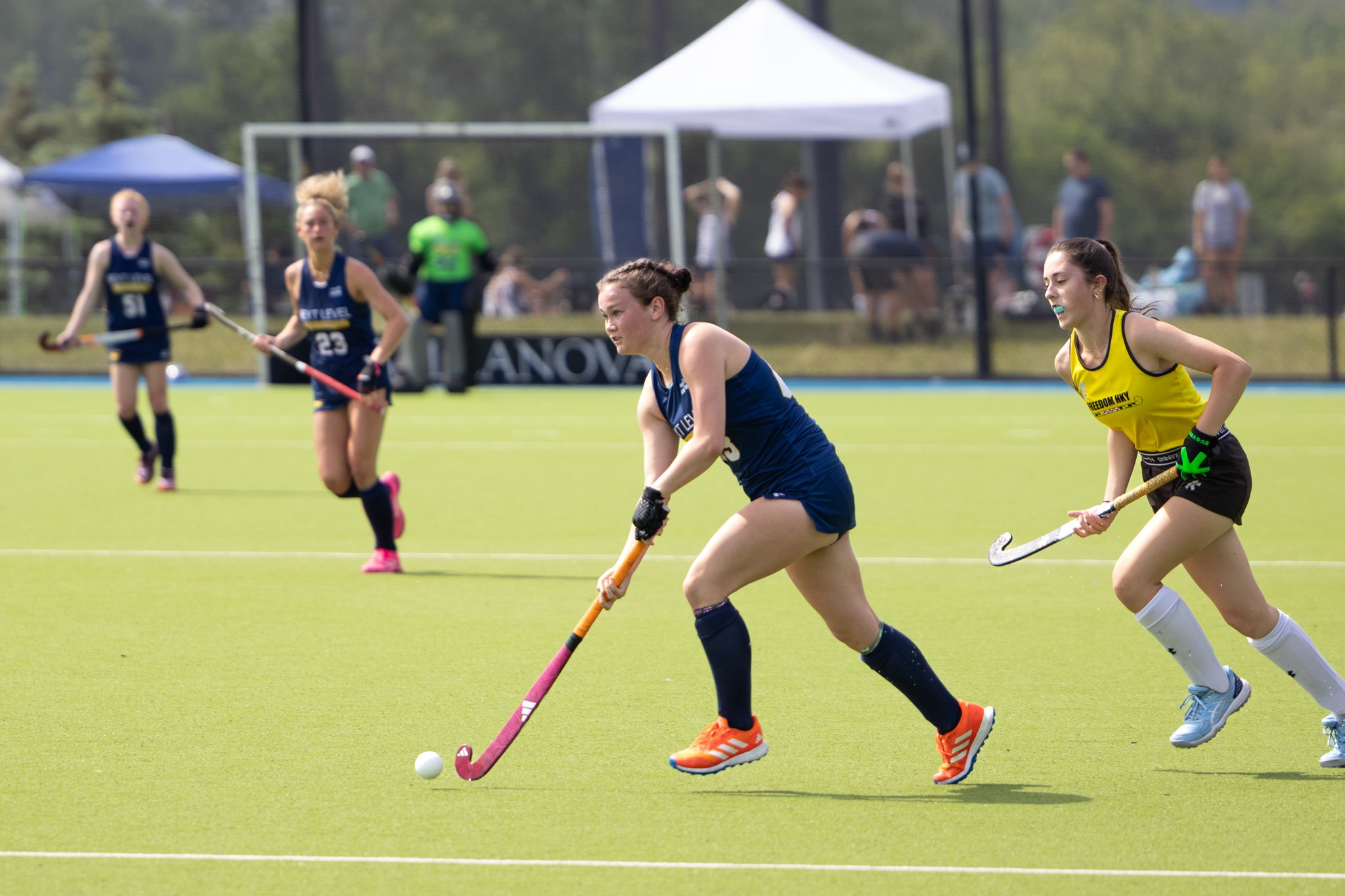 Female field hockey player dribbling ball on Astro turf