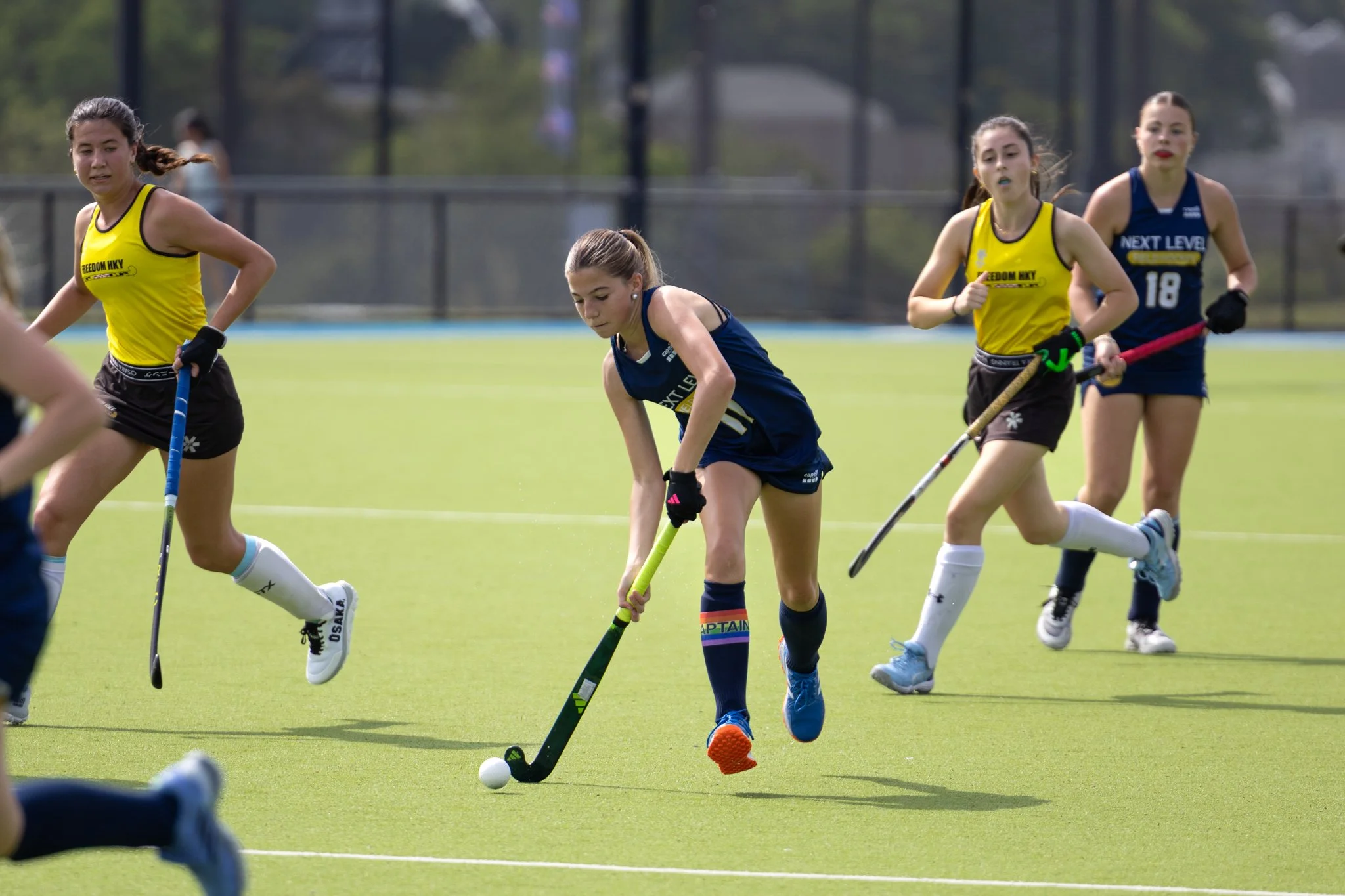 Female field hockey player dribbling ball on Astro turf