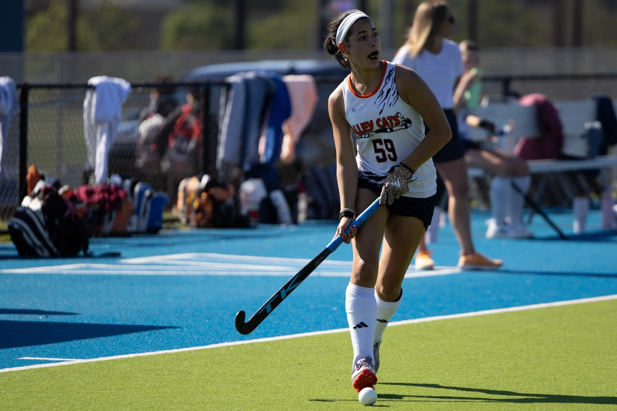 Female field hockey player dribbling ball on Astro turf
