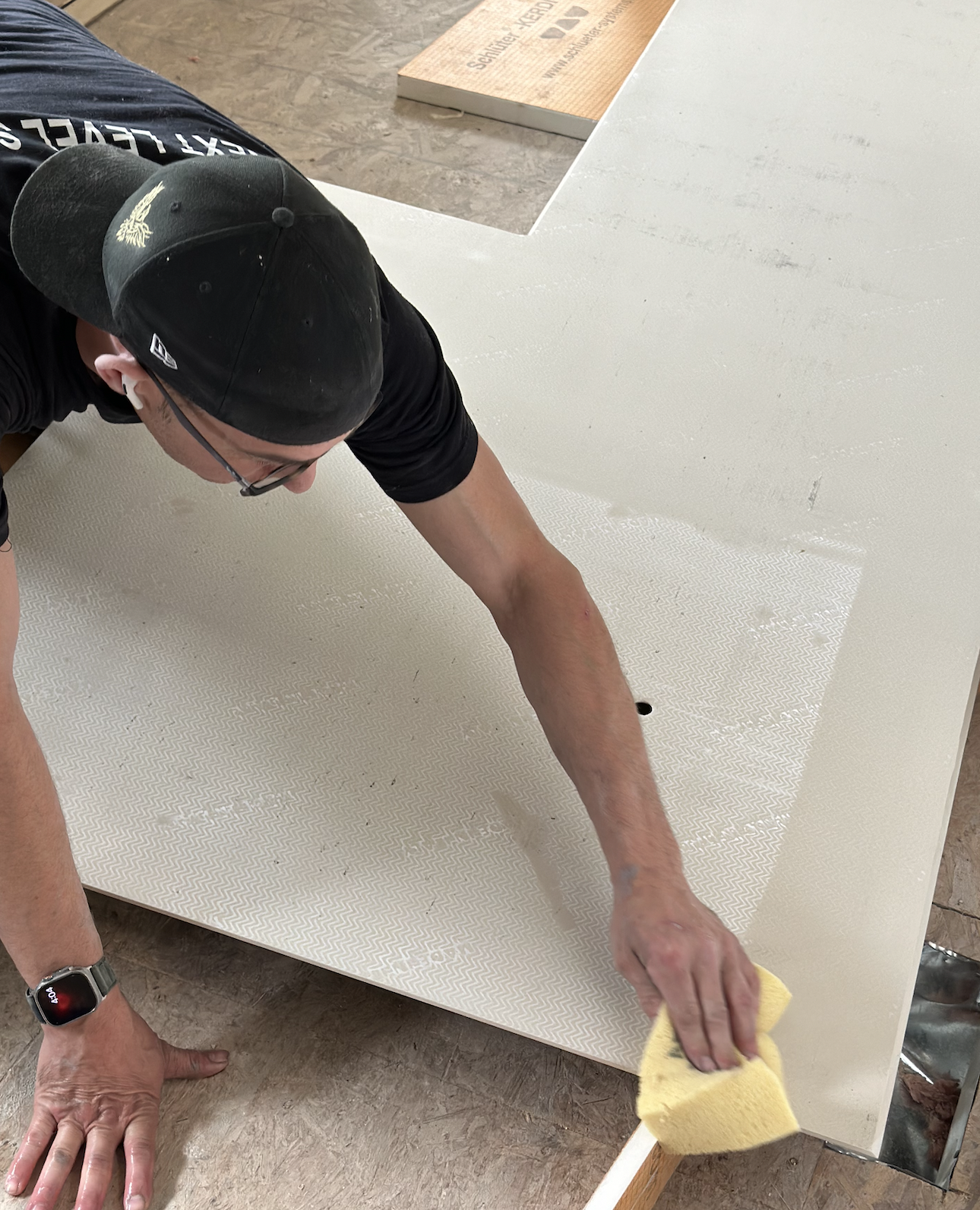 Adam uses a sponge to wet the back of the porcelain panel before applying thinset.