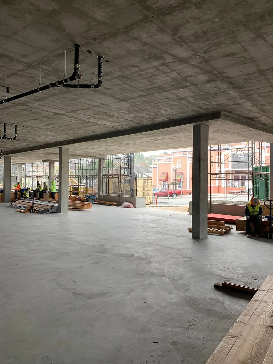 Construction site with workers in safety gear, scaffolding, and building materials inside a partially finished building