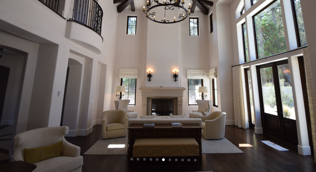 Elegant living room with high vaulted ceiling, large windows, a fireplace, and comfortable seating.