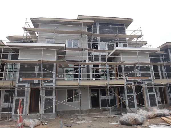 Under construction multi-story residential building with scaffolding and construction materials.