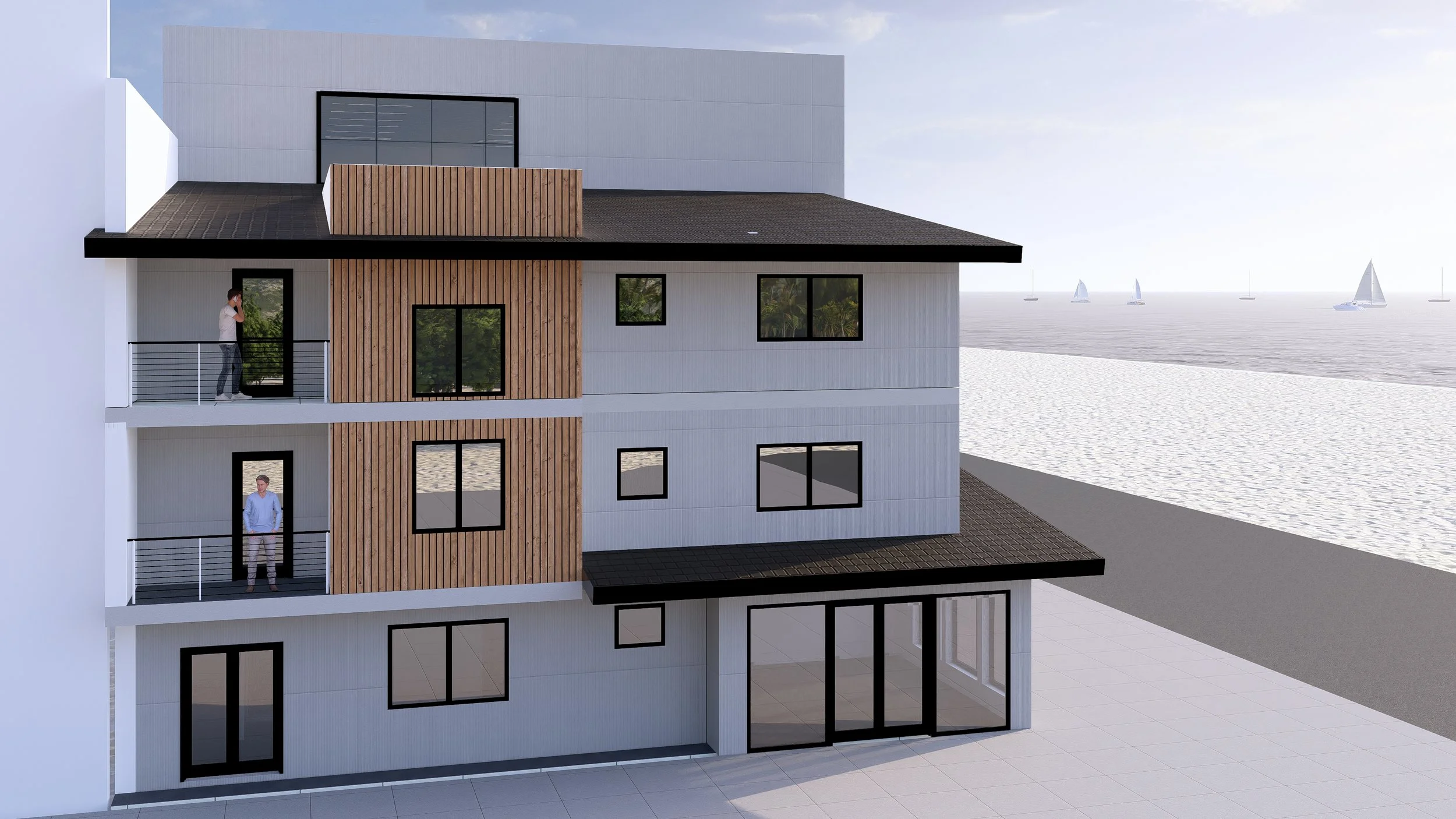 A modern multi-story building with balconies overlooking the beach and ocean, featuring white walls, black window frames, and wooden accents, with sailboats in the water and people visible on the balconies.