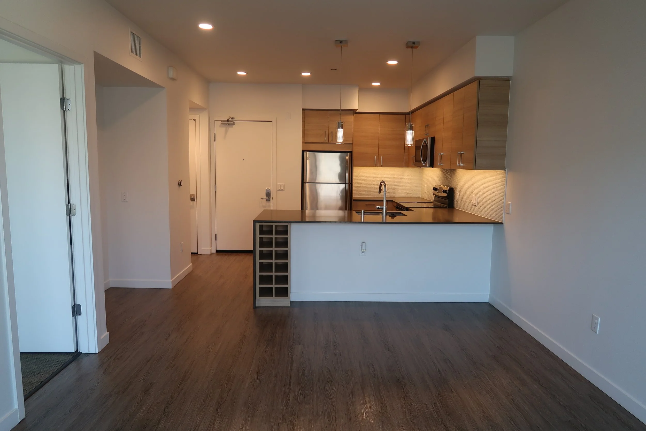 Modern kitchen with wooden cabinets, stainless steel appliances, and a small breakfast bar area.
