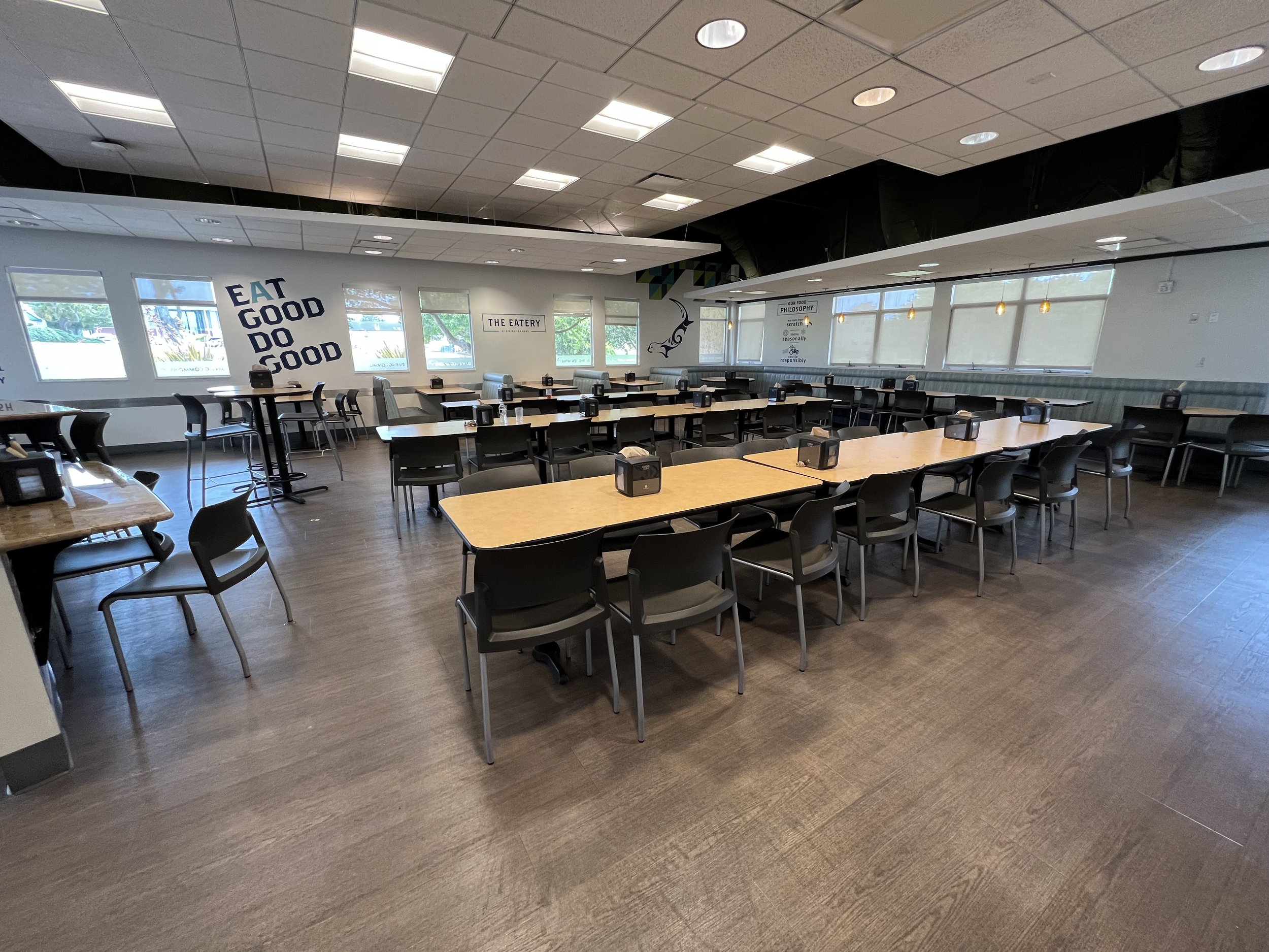Empty restaurant dining area with tables, chairs, and wall decorations.