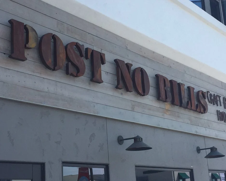Sign on a building that reads 'POST NO BILLS' in large, three-dimensional letters.