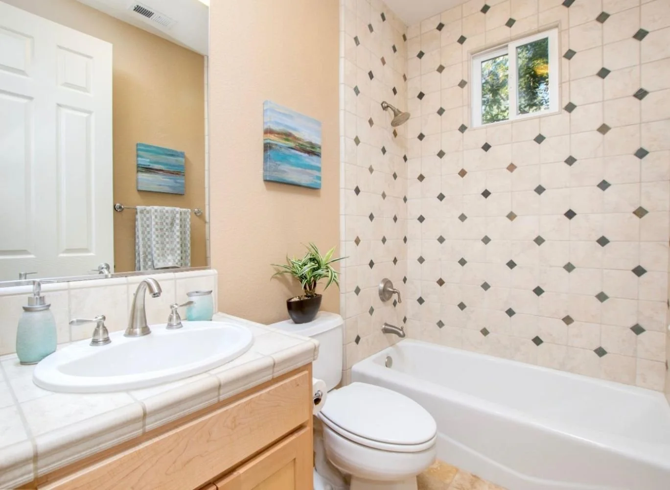 Bathroom with a sink, a toilet, and a bathtub with a tiled wall and window
