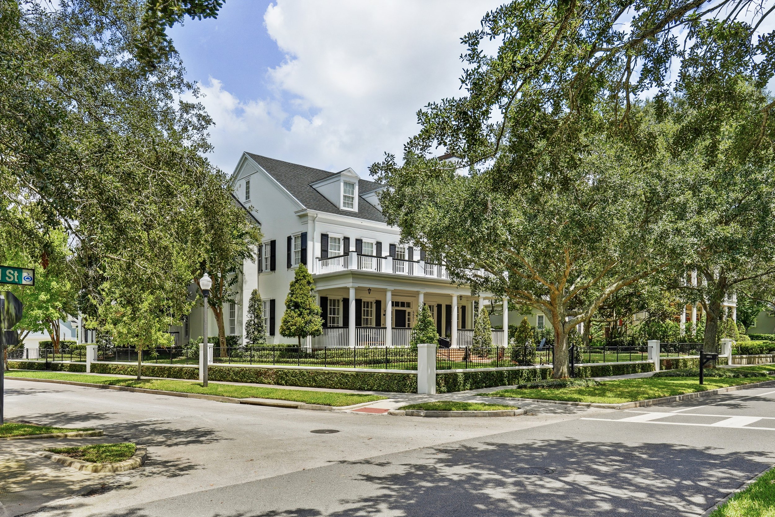  Set on a prominent corner homesite, this wider view captures the home’s impressive scale, mature tree canopy, manicured landscaping and timeless architectural presence. 