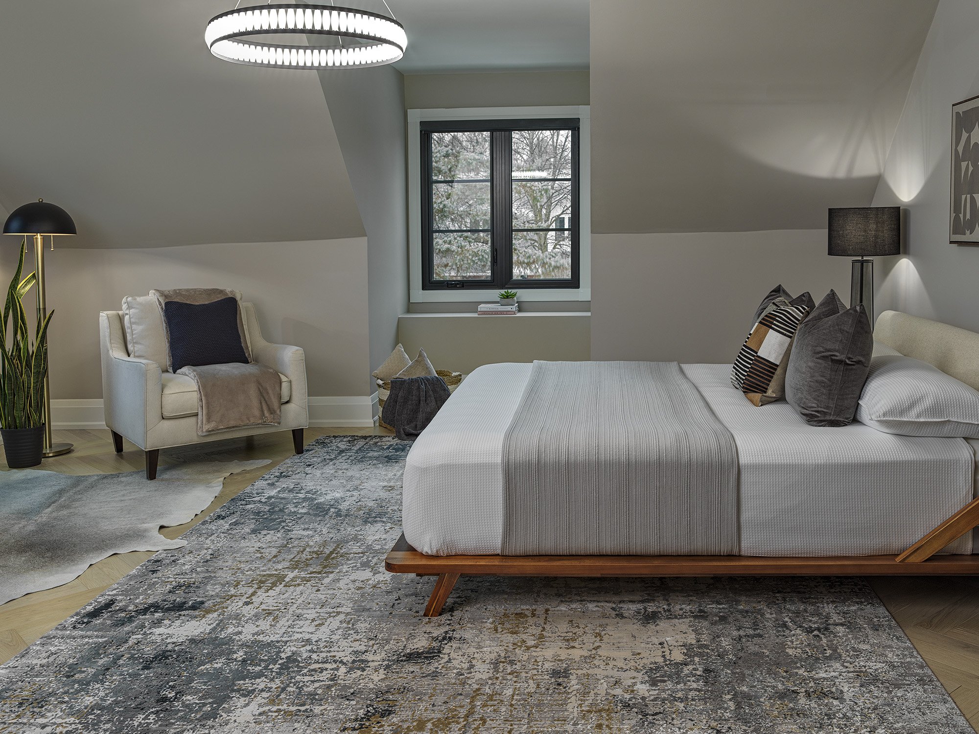 Large bedroom with modern bedding and lighting with cozy seating.