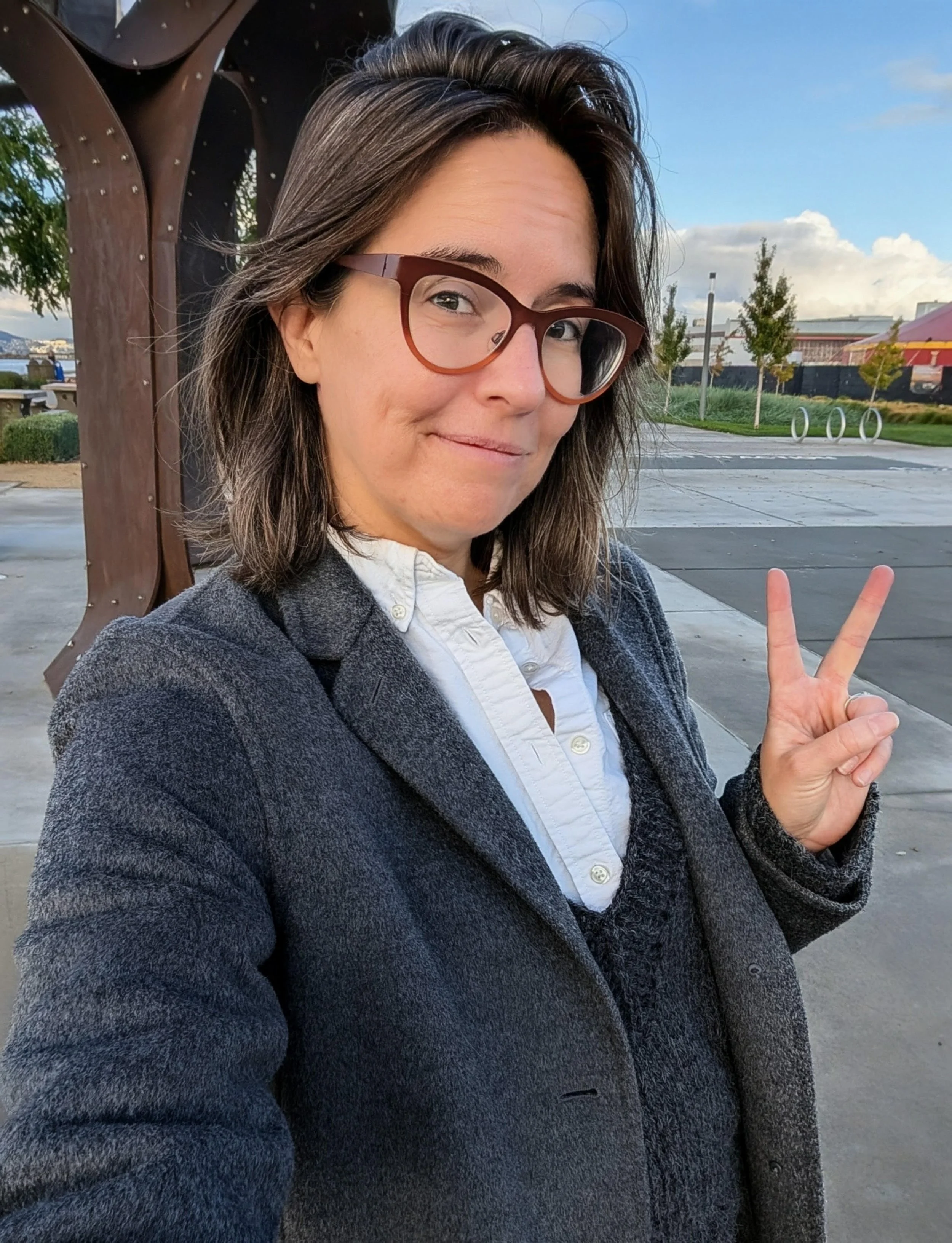 Jessica smiles and has two fingers up in a peace sign.