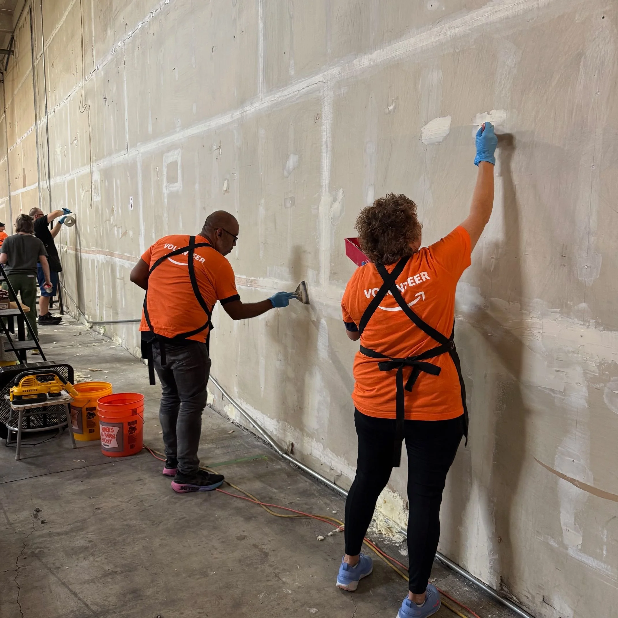 two people filling holes in a wall with spackle