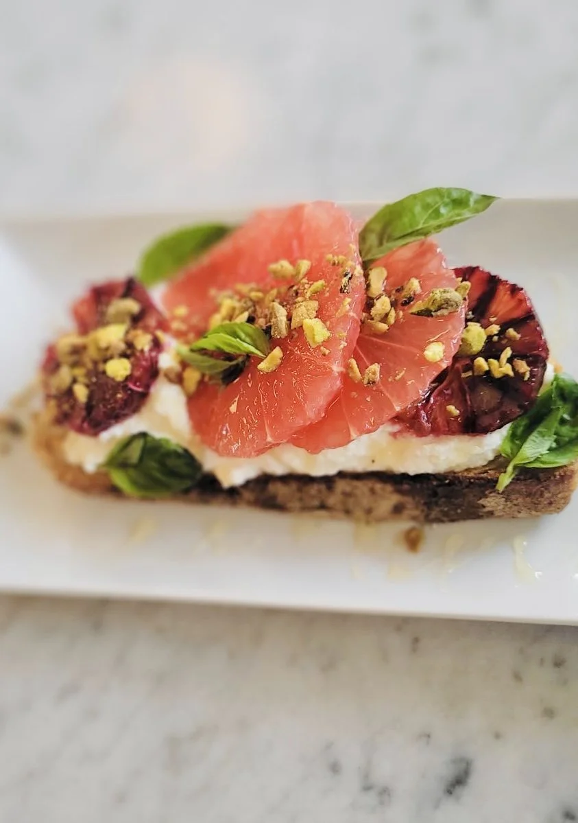 Toast avec fromage, tranches de tomate, basilic, pistaches concassées et fruits rouges.