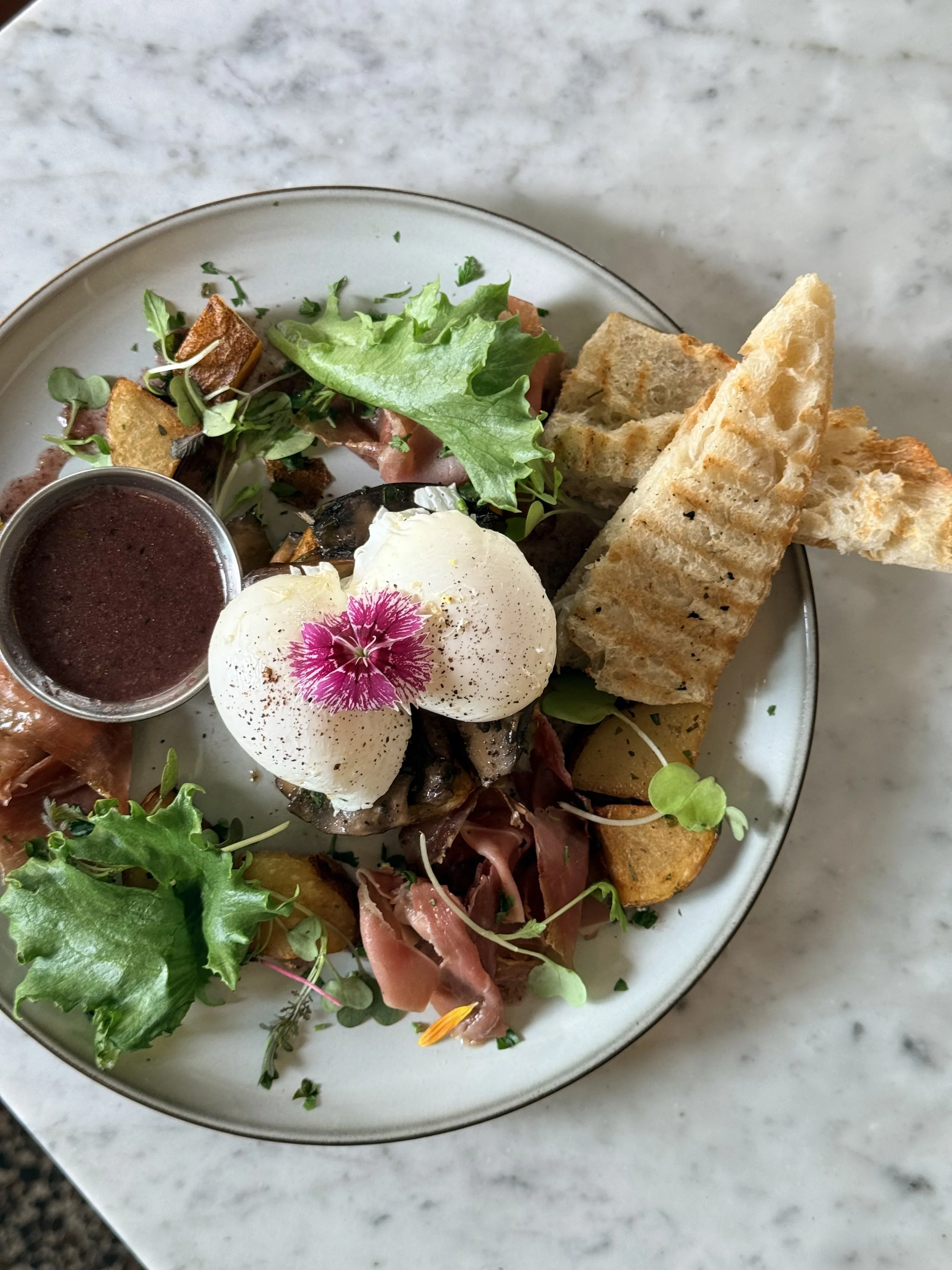Restaurant de quartier dans Villeray, menu frites, tartare de viande crue avec un œuf cru dessus, pain grillé, et un petit bol de mayonnaise, posée sur une surface en marbre.