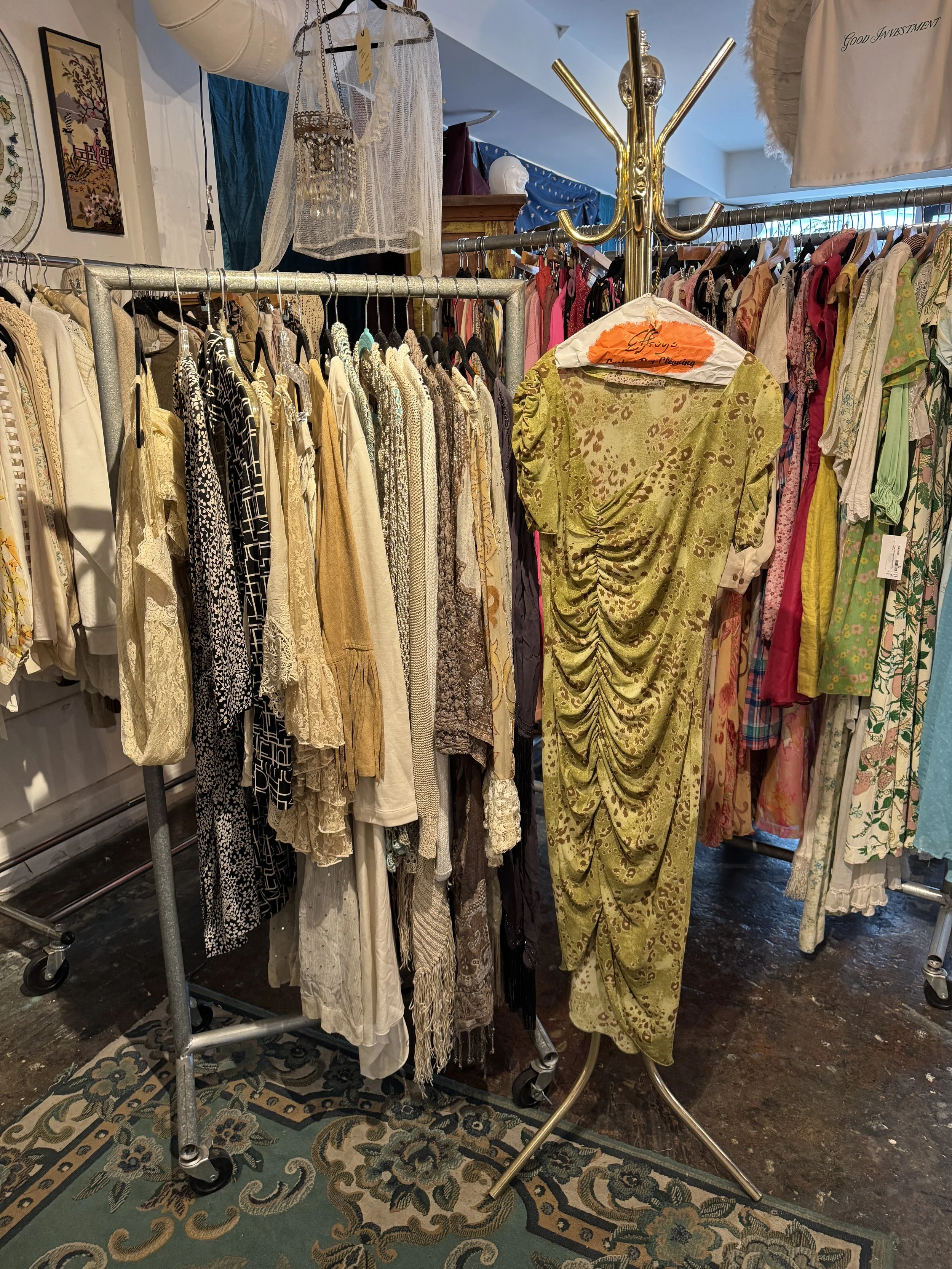 Clothing rack with vintage dresses and garments in a thrift store or boutique.