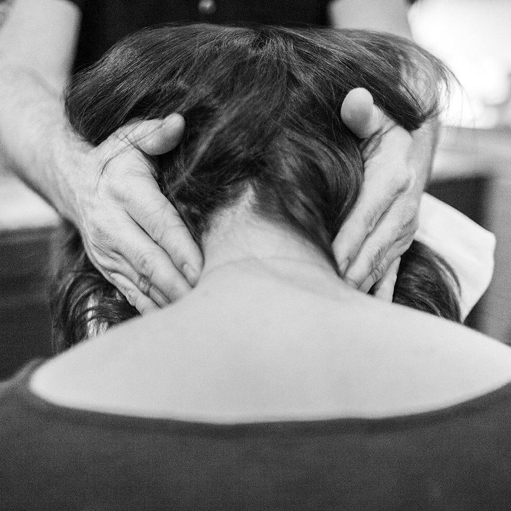  a woman receiving a massage to the sides of her neck and looks deeply relaxed 