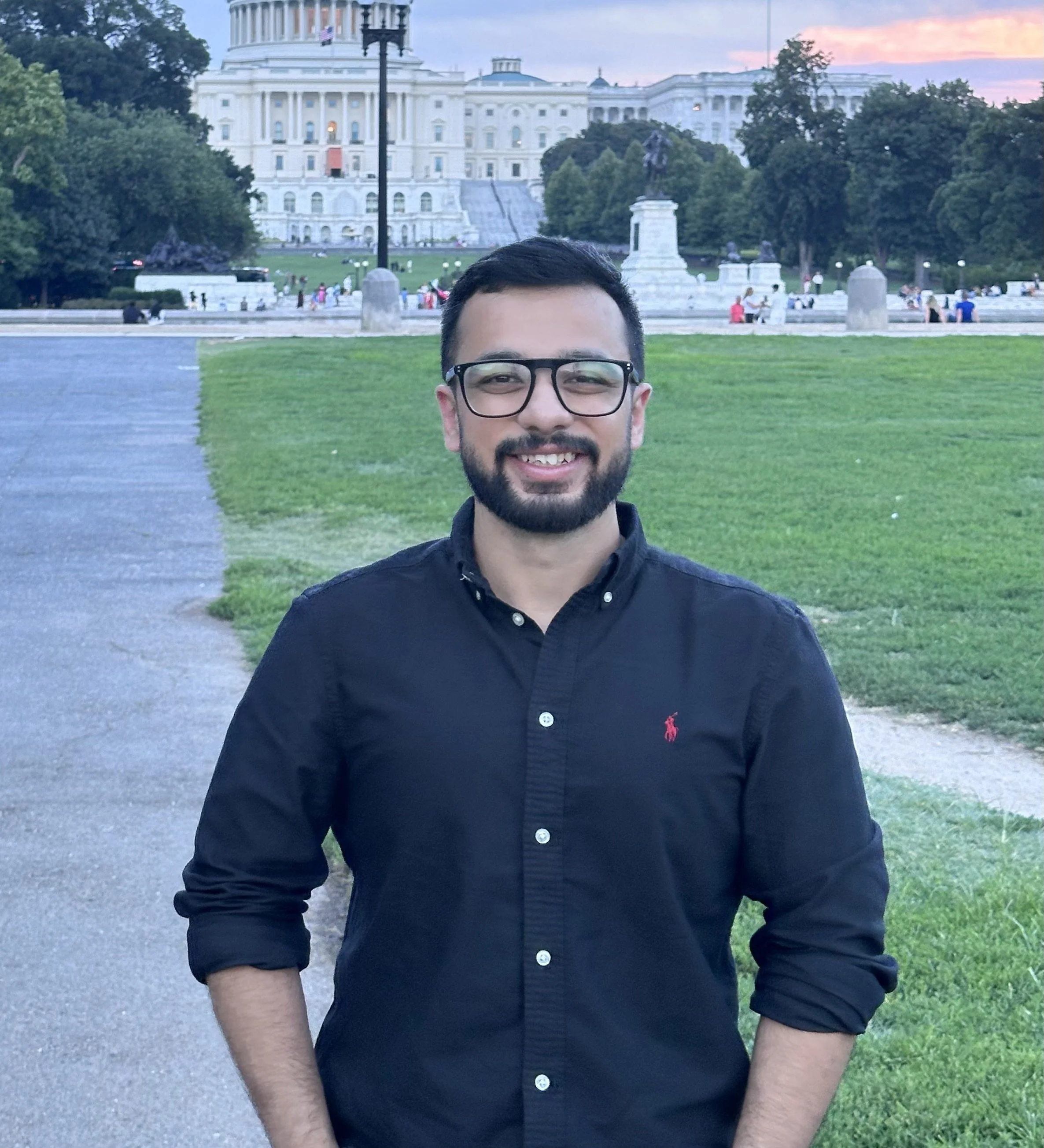 Sahib Narang standing in front of the U.S. Capitol building at sunset, wearing a black button-down shirt with rolled-up sleeves.