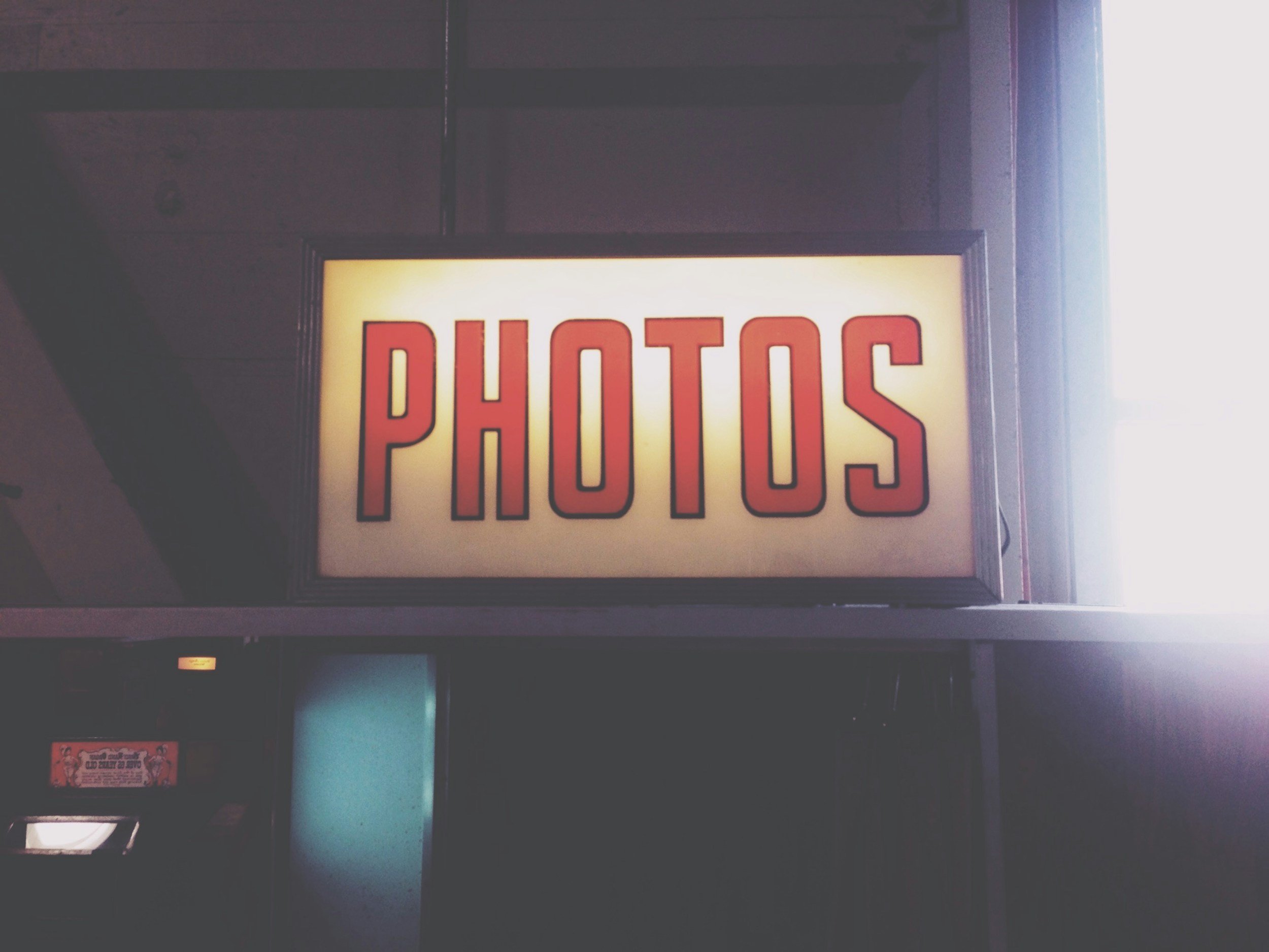 Close-up of a lit sign with the word 'PHOTOS' in red letters.