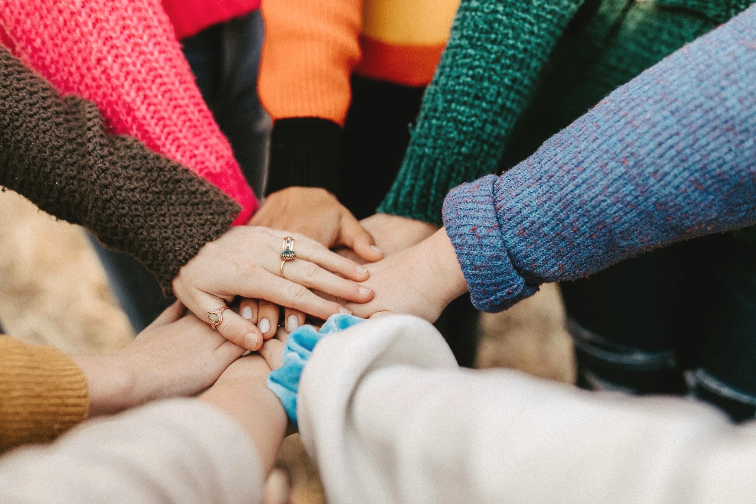 Multiple hands joined together in a circle, symbolizing unity and teamwork.