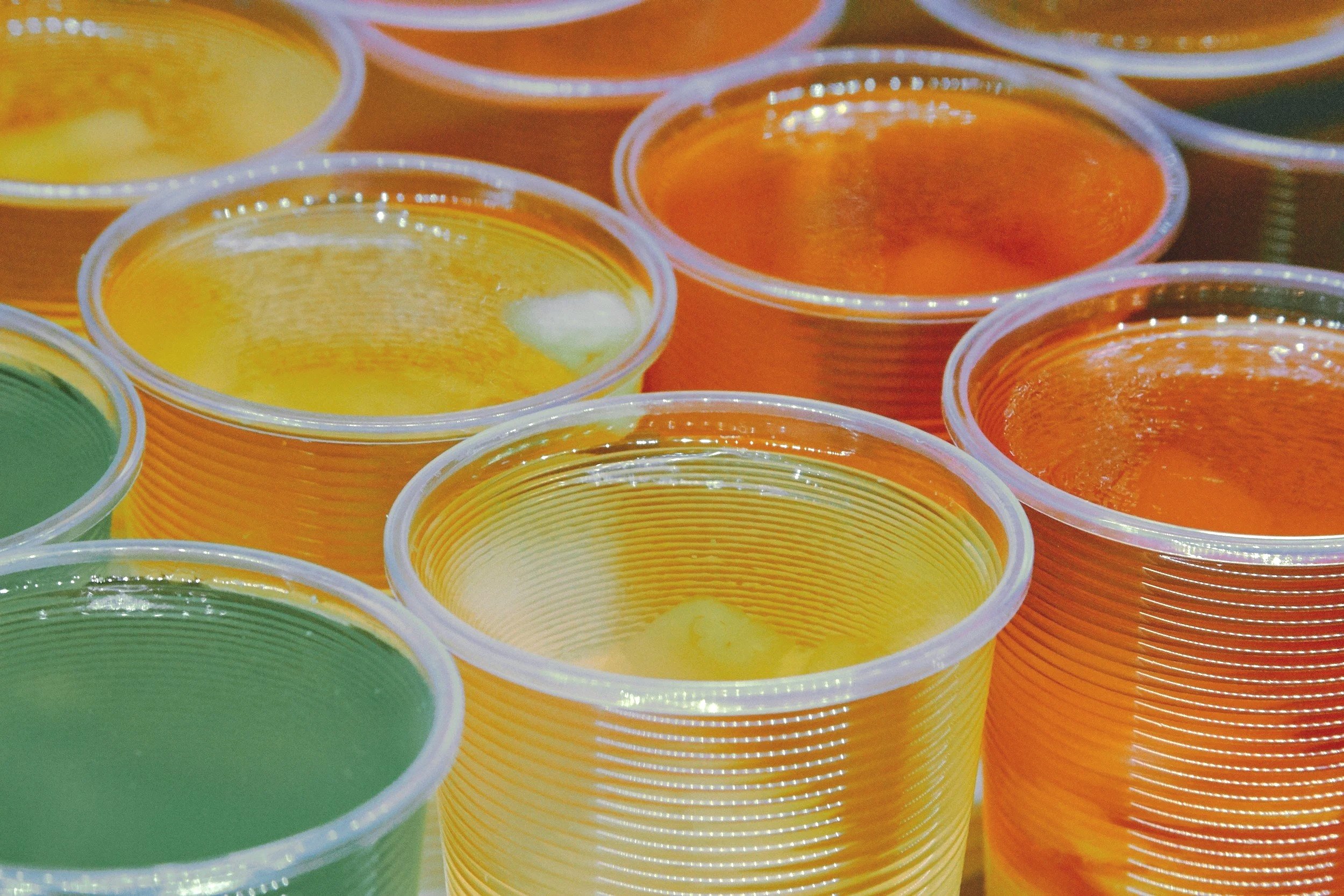 Multiple colorful plastic cups filled with jelly in various colors including yellow, orange, and green.