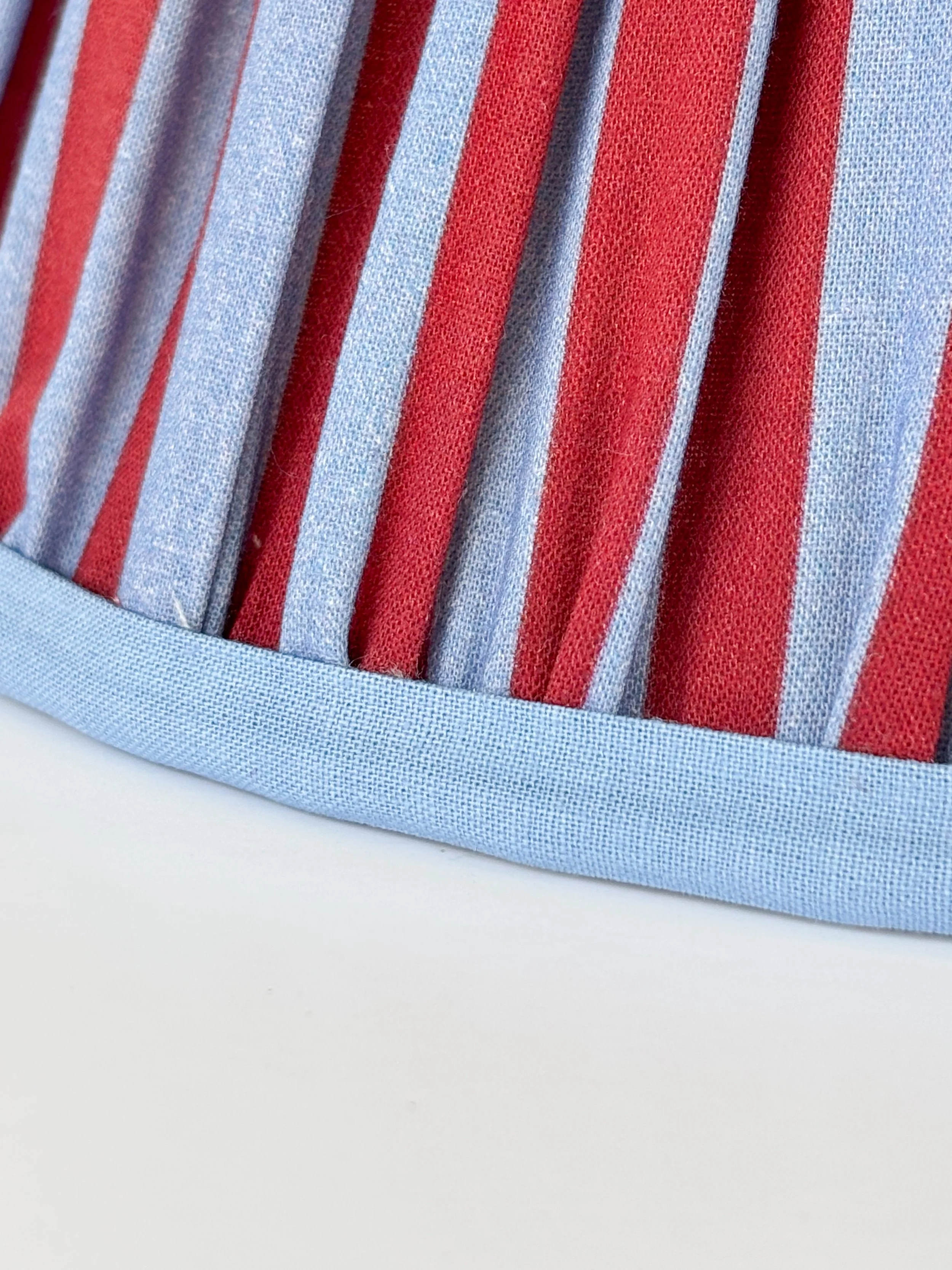 Empire lampshade with light blue trim and bold red fabric panels.
