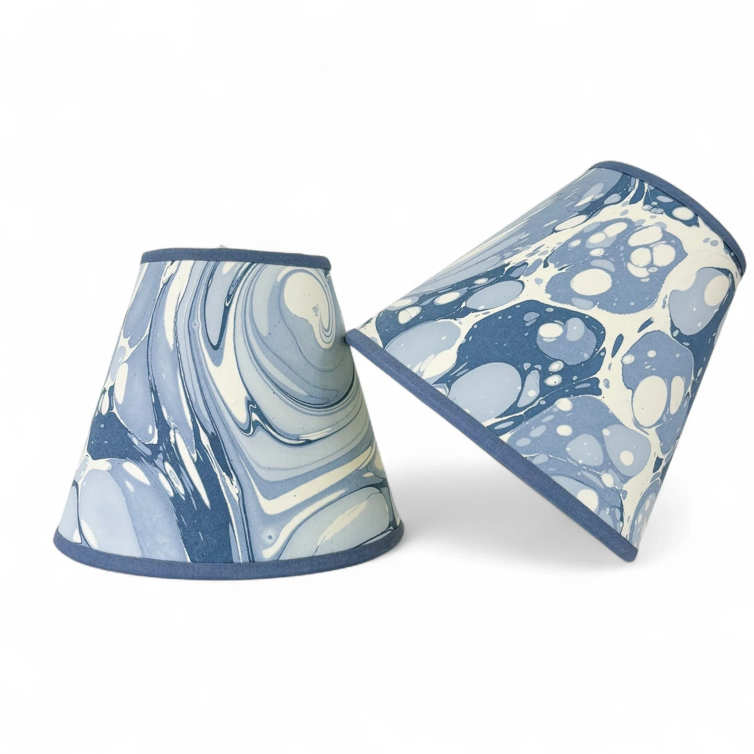 Pair of blue marbled clip-on chandelier shades photographed on a white background.