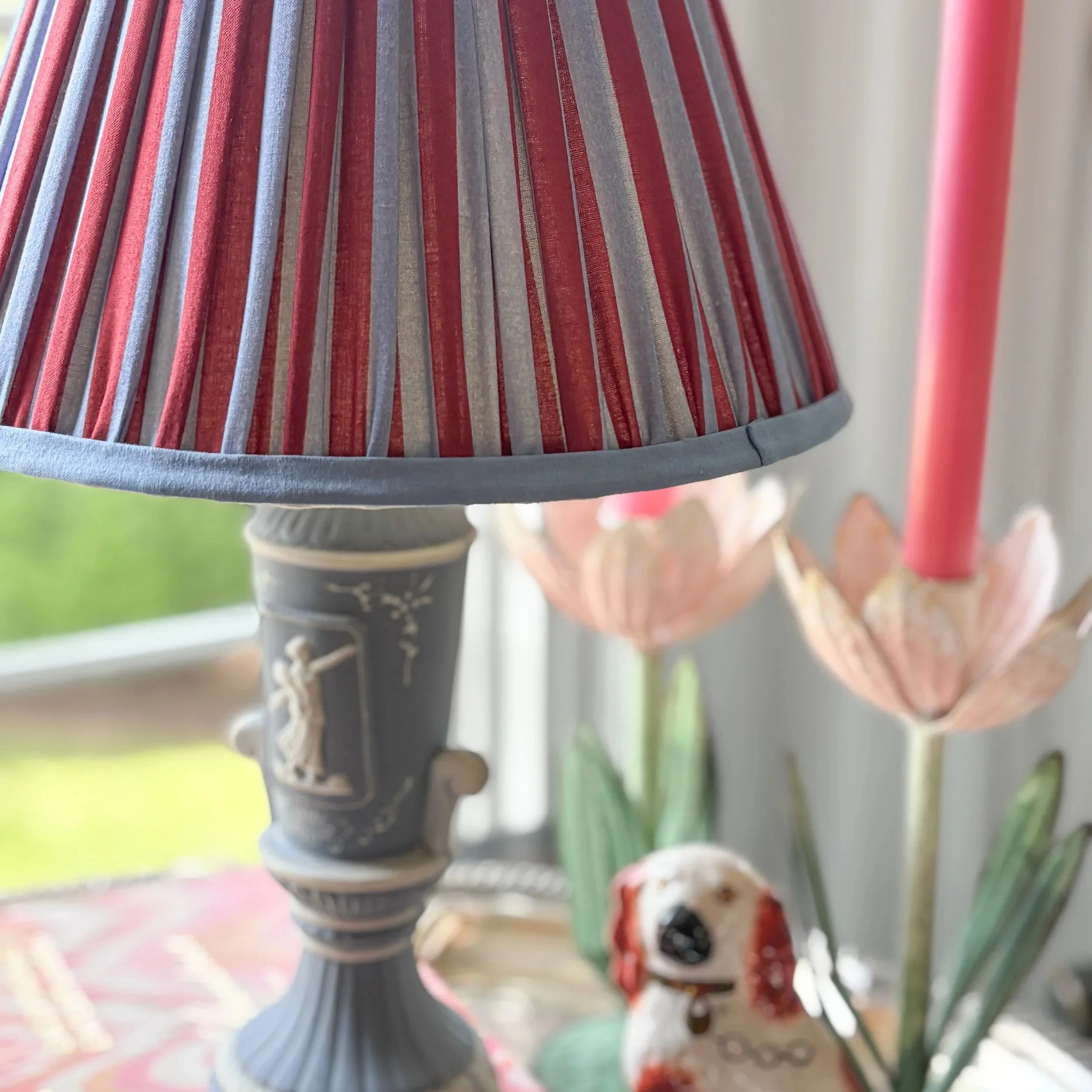 Colorful striped lampshade with red and blue pleated construction on Wedgewood Lamp base.