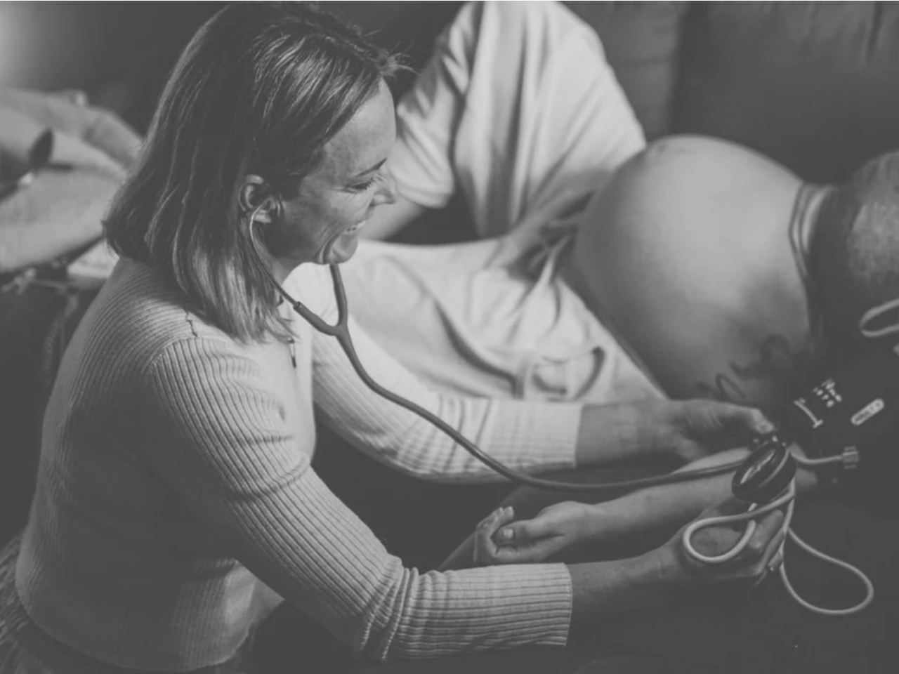 Midwife listening to a pregnant woman’s baby with a stethoscope during a prenatal check.
