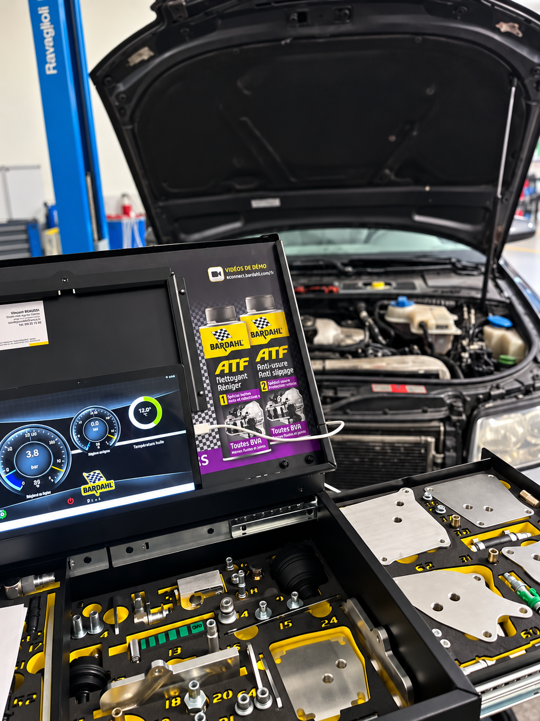 Voiture avec capot ouvert et outil de diagnostic automobile en atelier.