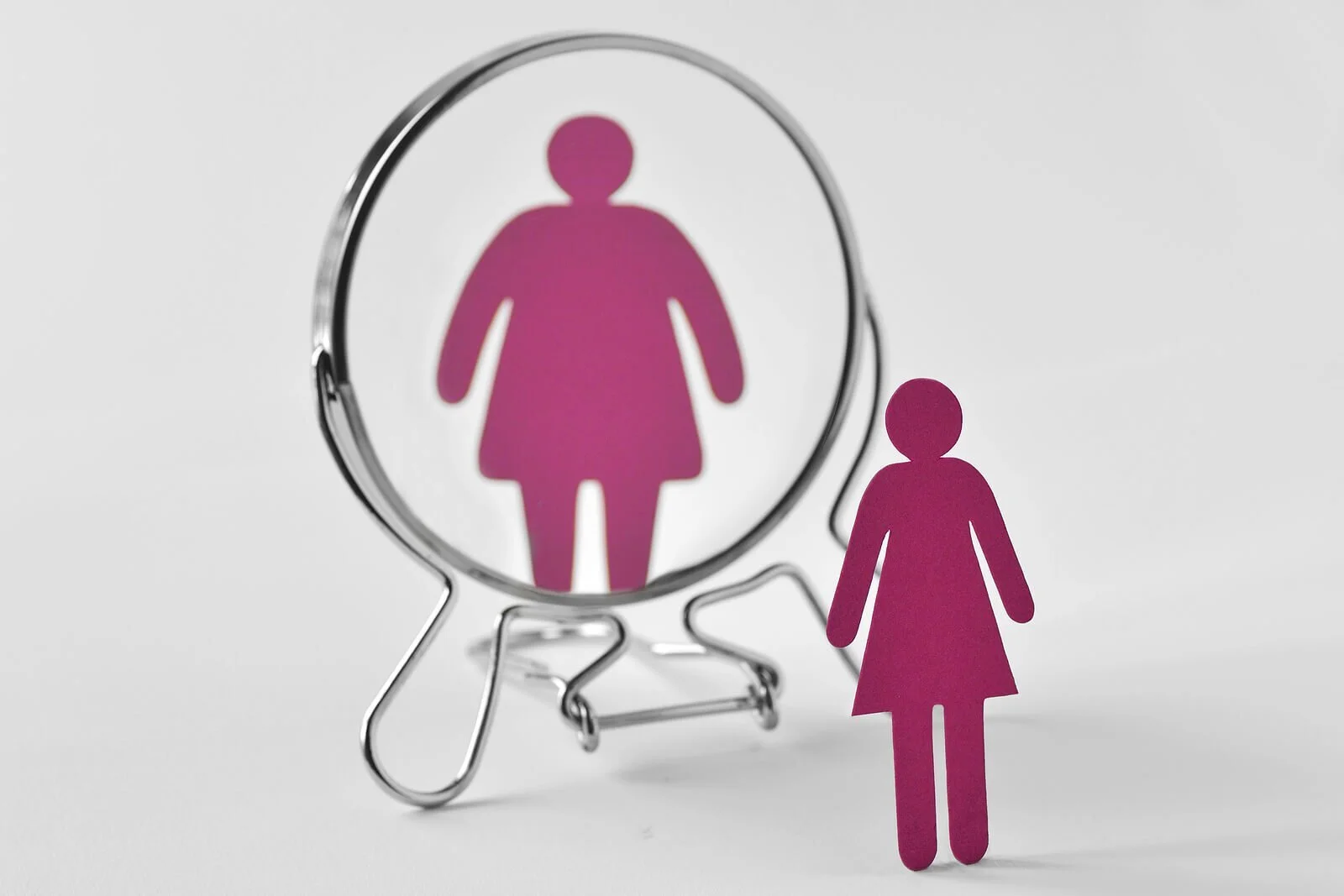 Woman in mirror feeling bigger. Body image issues can get in the way of body acceptance in Pennsylvania. Let us help. Learn from an eating disorder therapist how to improve body image today!