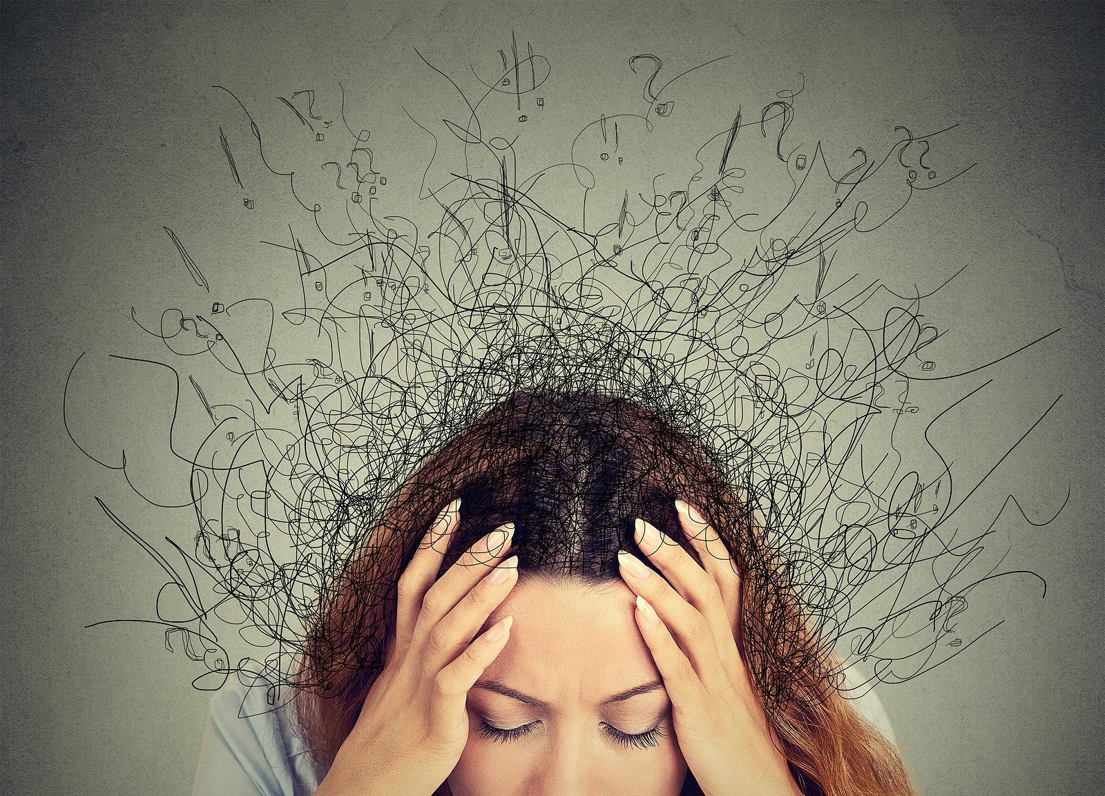 A woman holds her head as she is surrounded by exclamation points and question marks around her head. This could represent other comorbidities that can occur with eating disorders. Contact a disordered eating therapist in montgomery county, pa