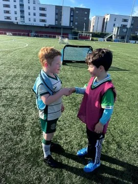 Two children shaking hands after a football match